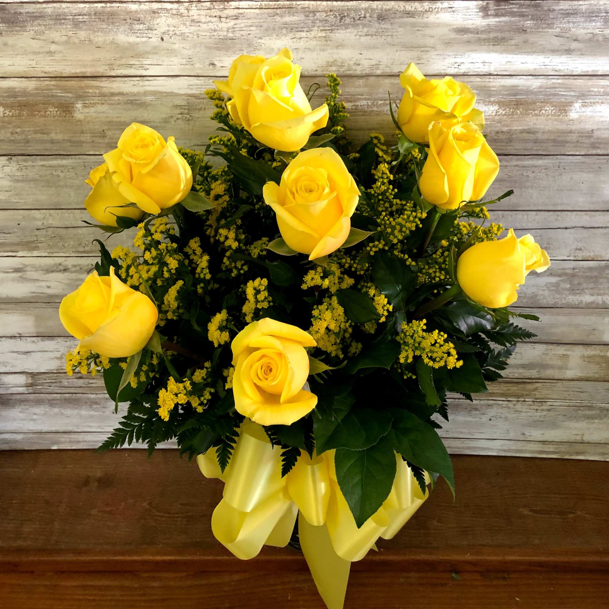 Bouquet of yellow roses with a yellow ribbon in a vase