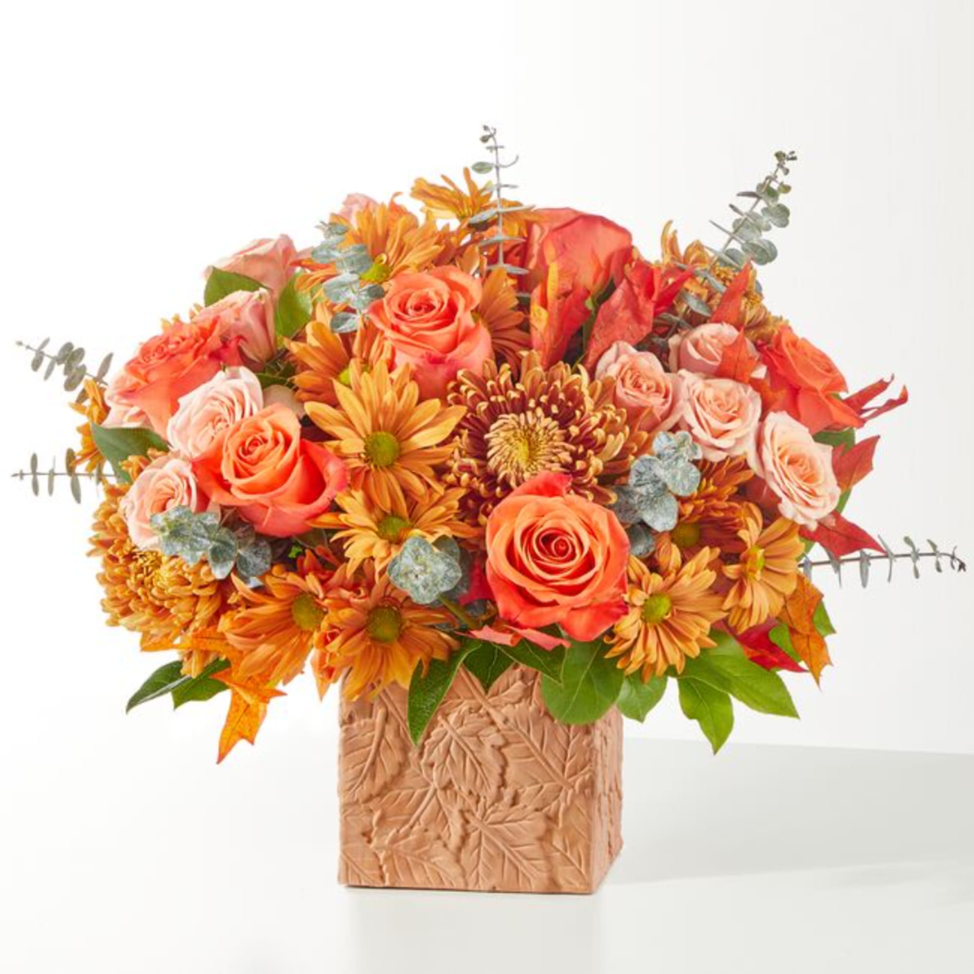 Orange roses and mums in a textured square vase