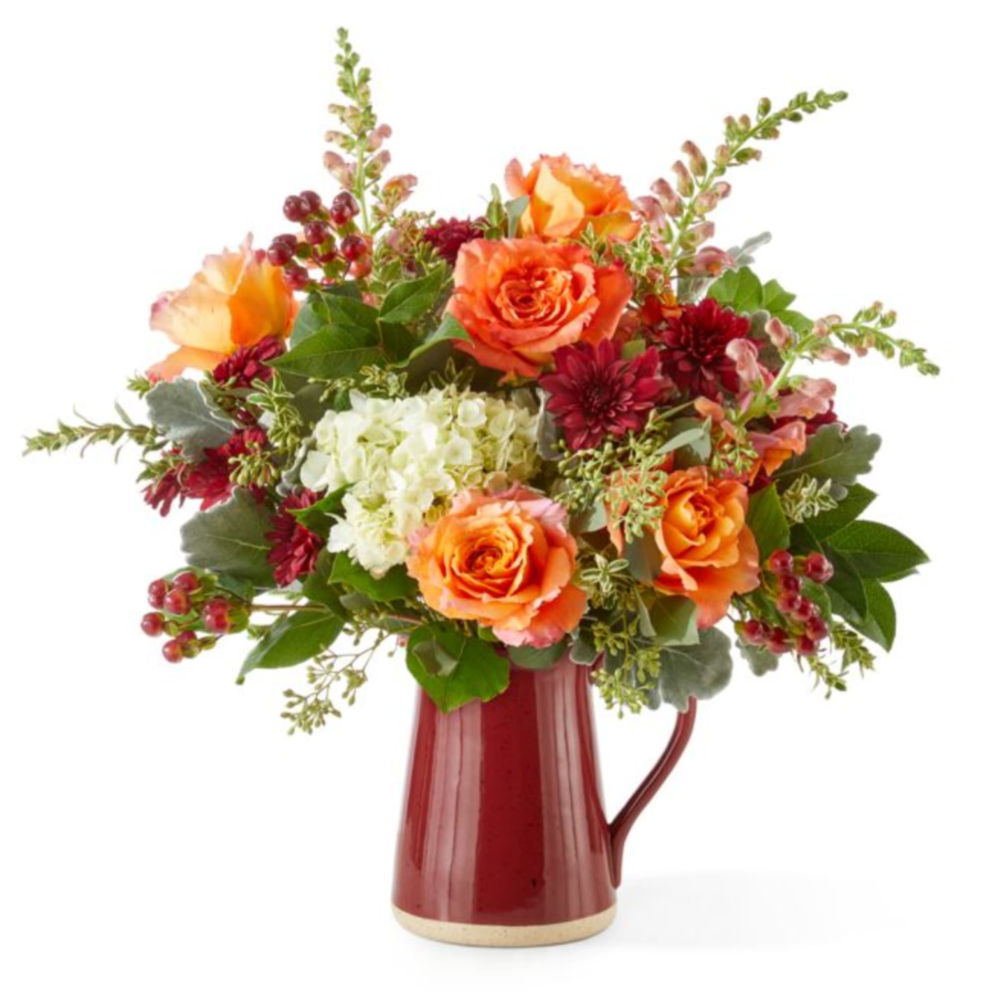 Orange and burgundy flower arrangement in a red pitcher vase