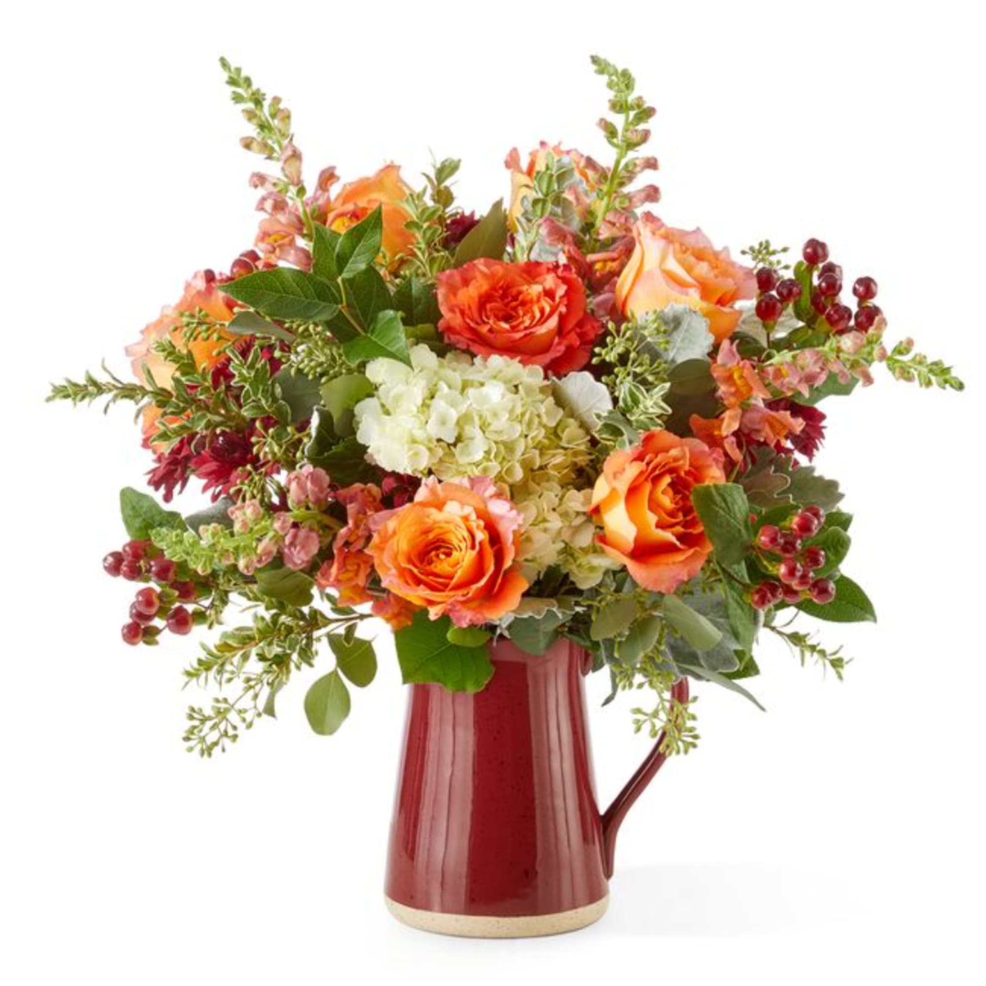 Orange roses and white hydrangea in a red ceramic pitcher vase