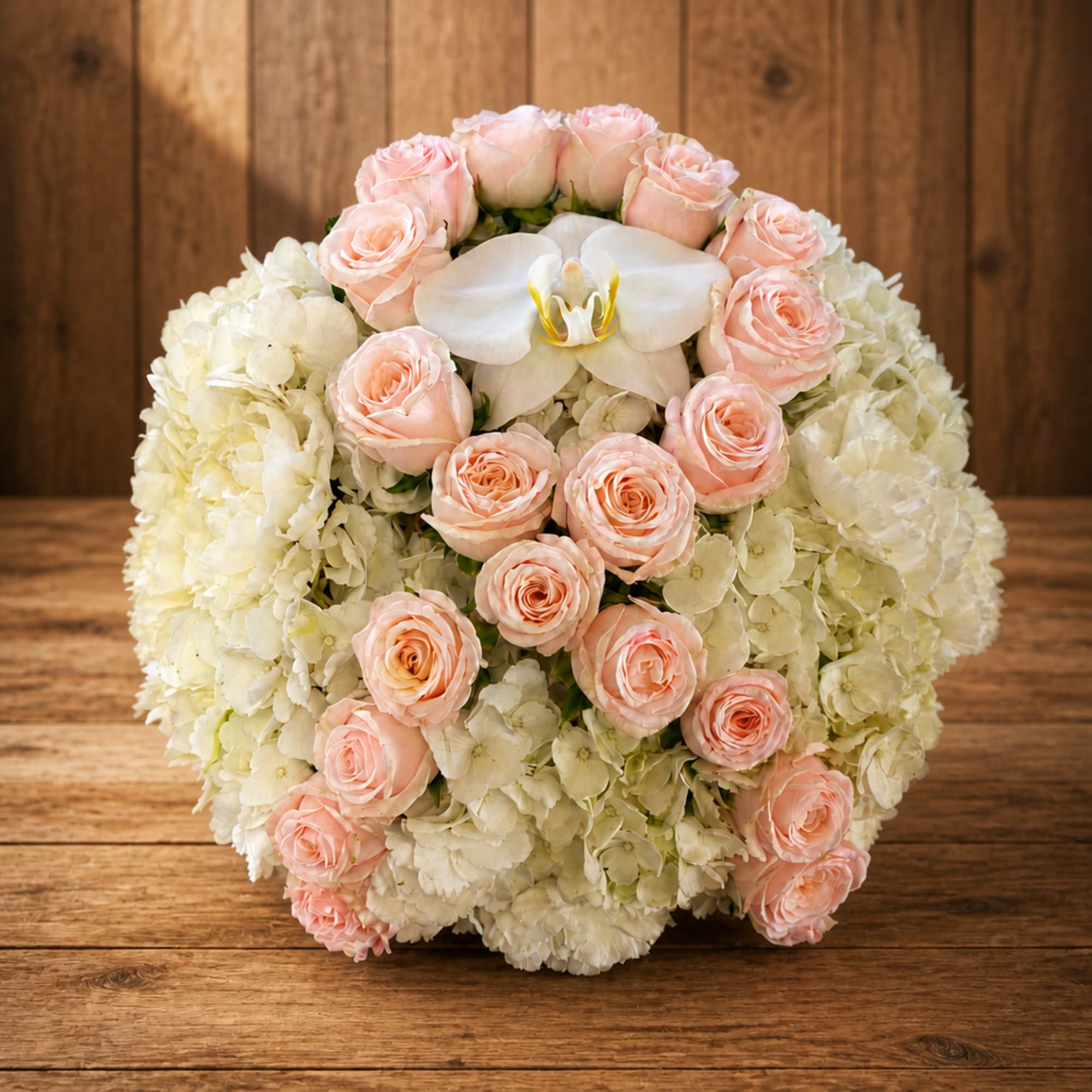 Round bouquet of pale pink roses and white hydrangeas with a white orchid center