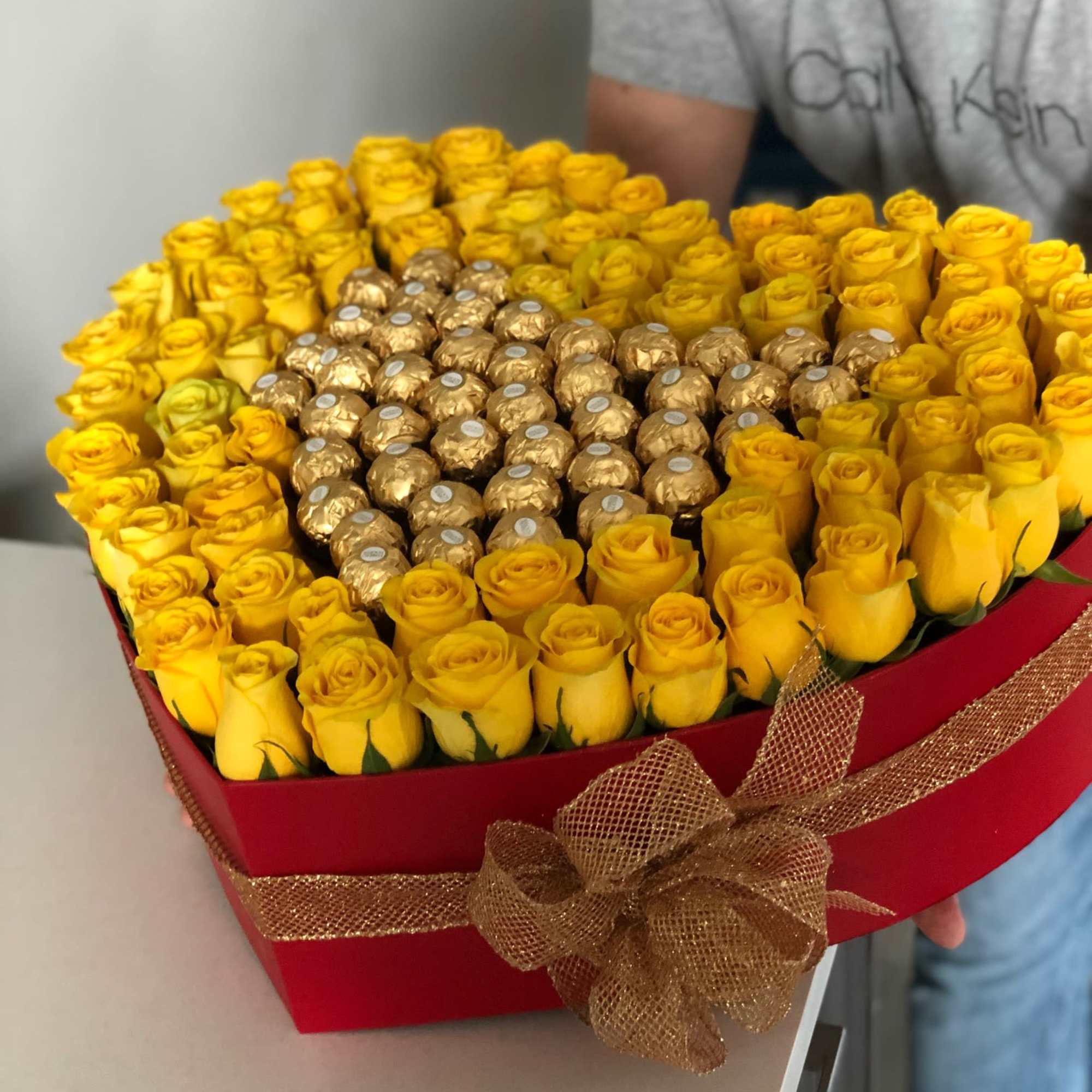 Heart-shaped box of yellow roses with gold-wrapped chocolates in the center