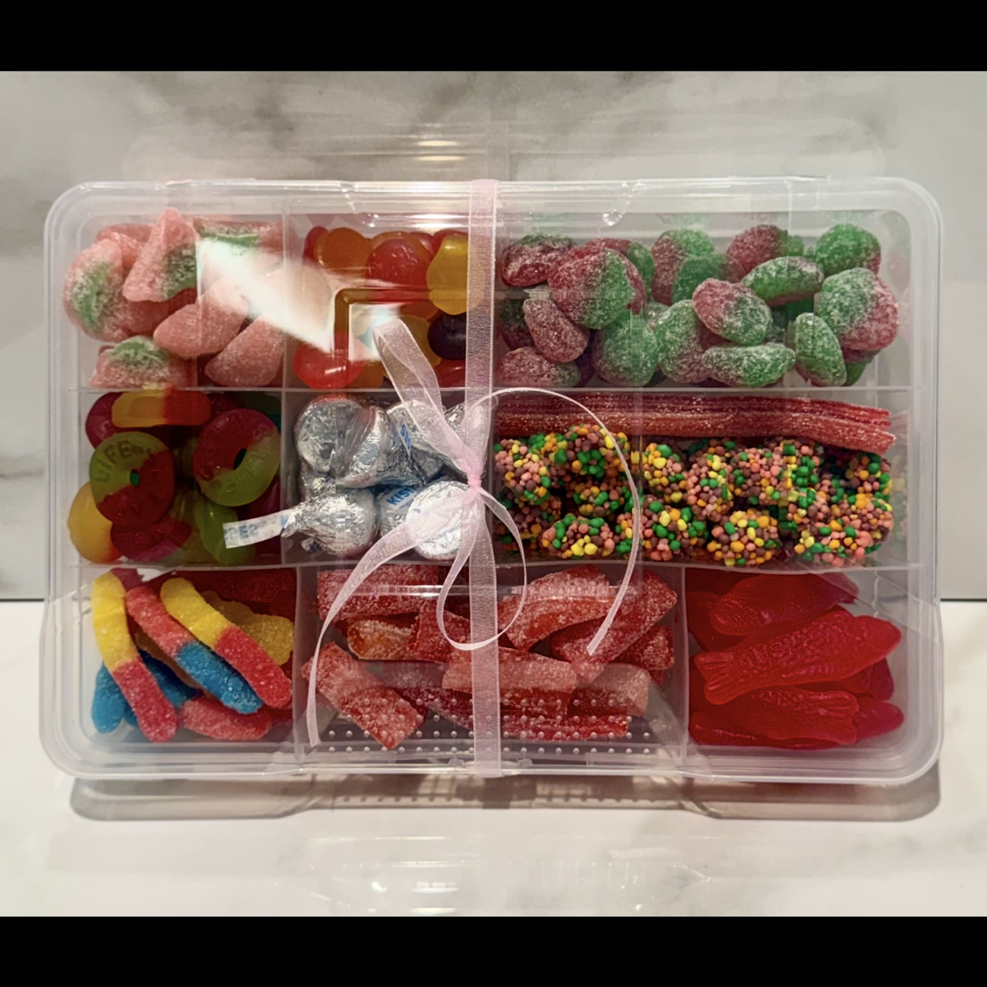 Clear gift box of assorted colorful candies tied with a ribbon