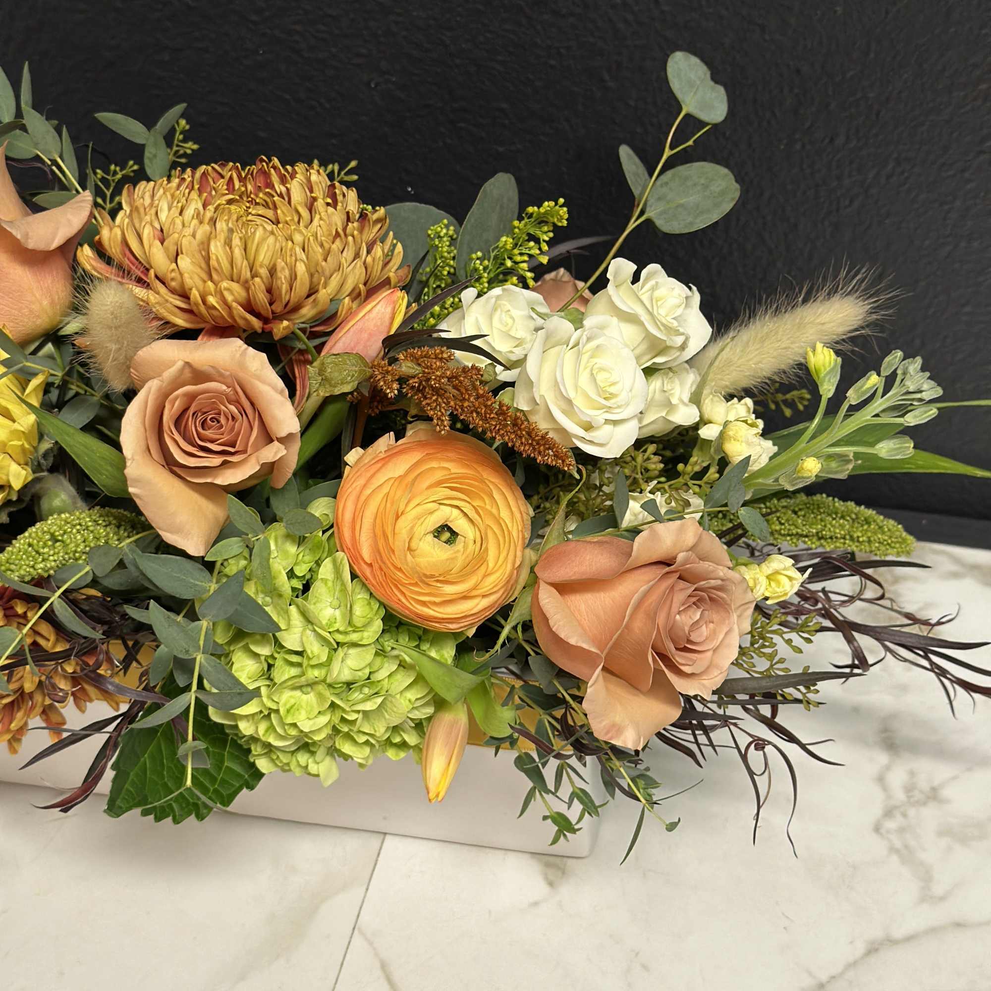 Mixed bouquet with peach roses, white roses, and orange blooms