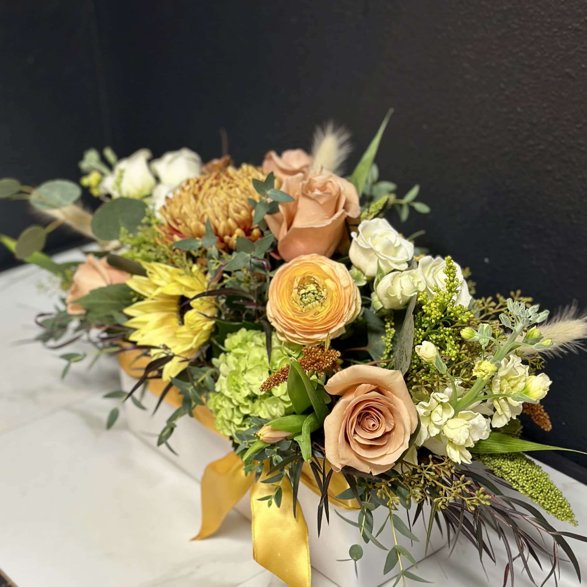 Peach and white floral arrangement in a white box with a yellow ribbon