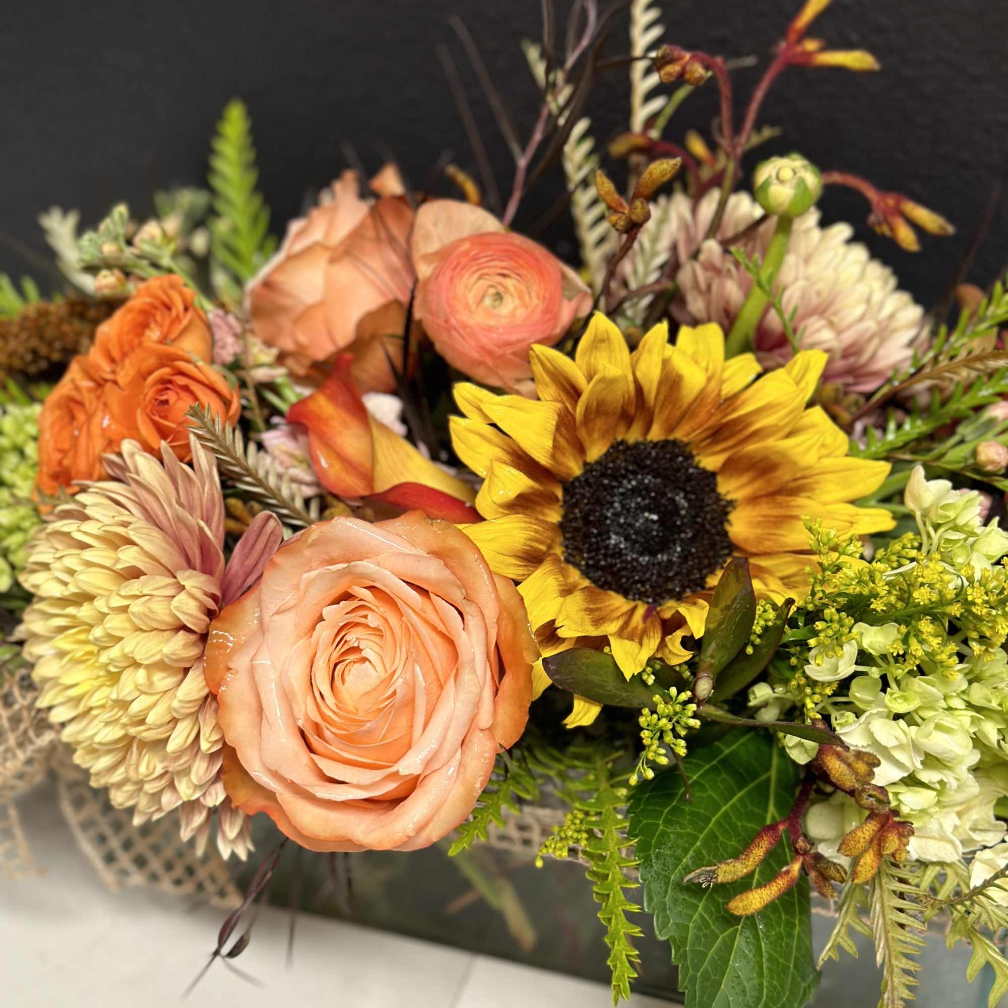 Mixed bouquet with peach roses, a sunflower, and pale chrysanthemums
