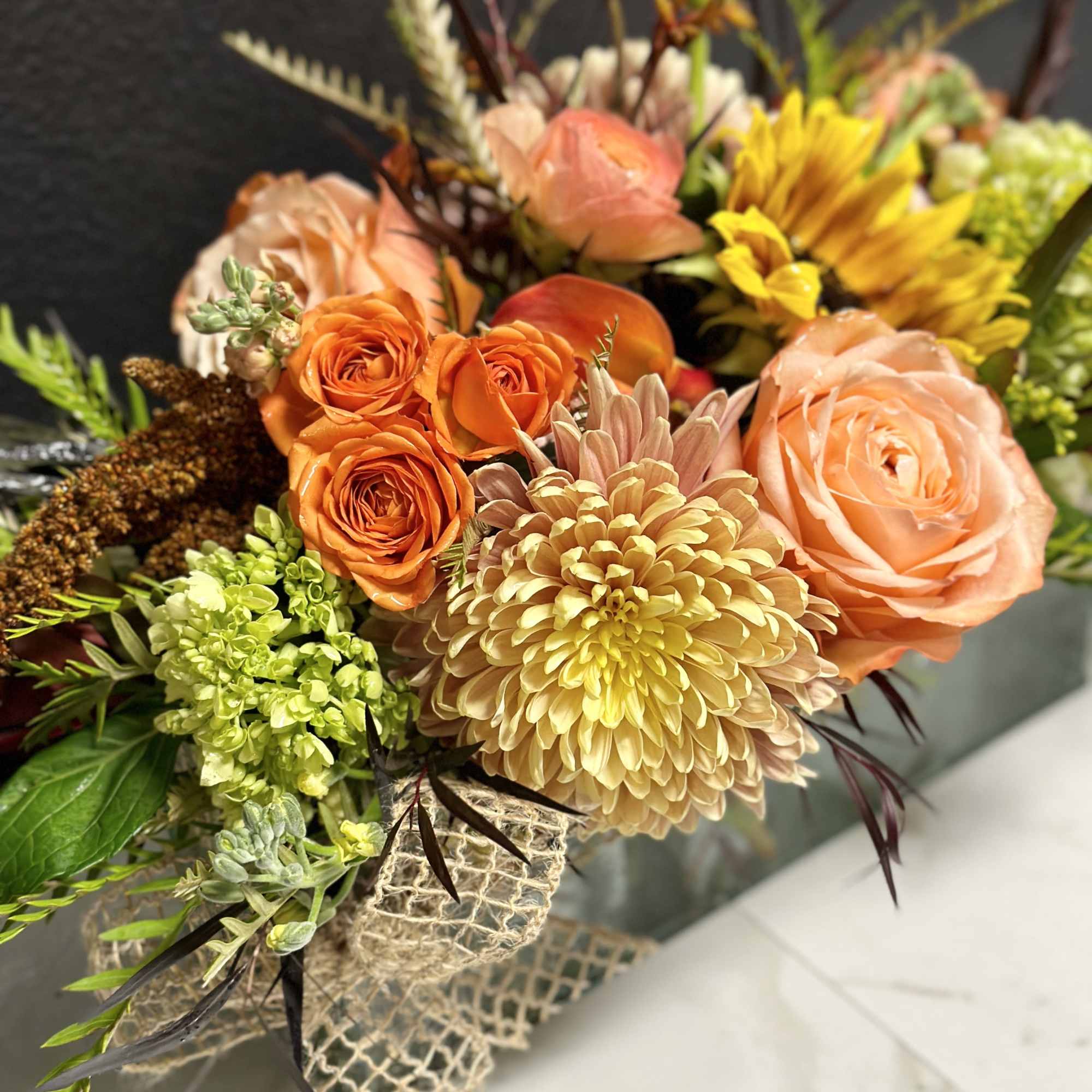 Bouquet of orange and peach flowers with yellow blooms and textured greenery