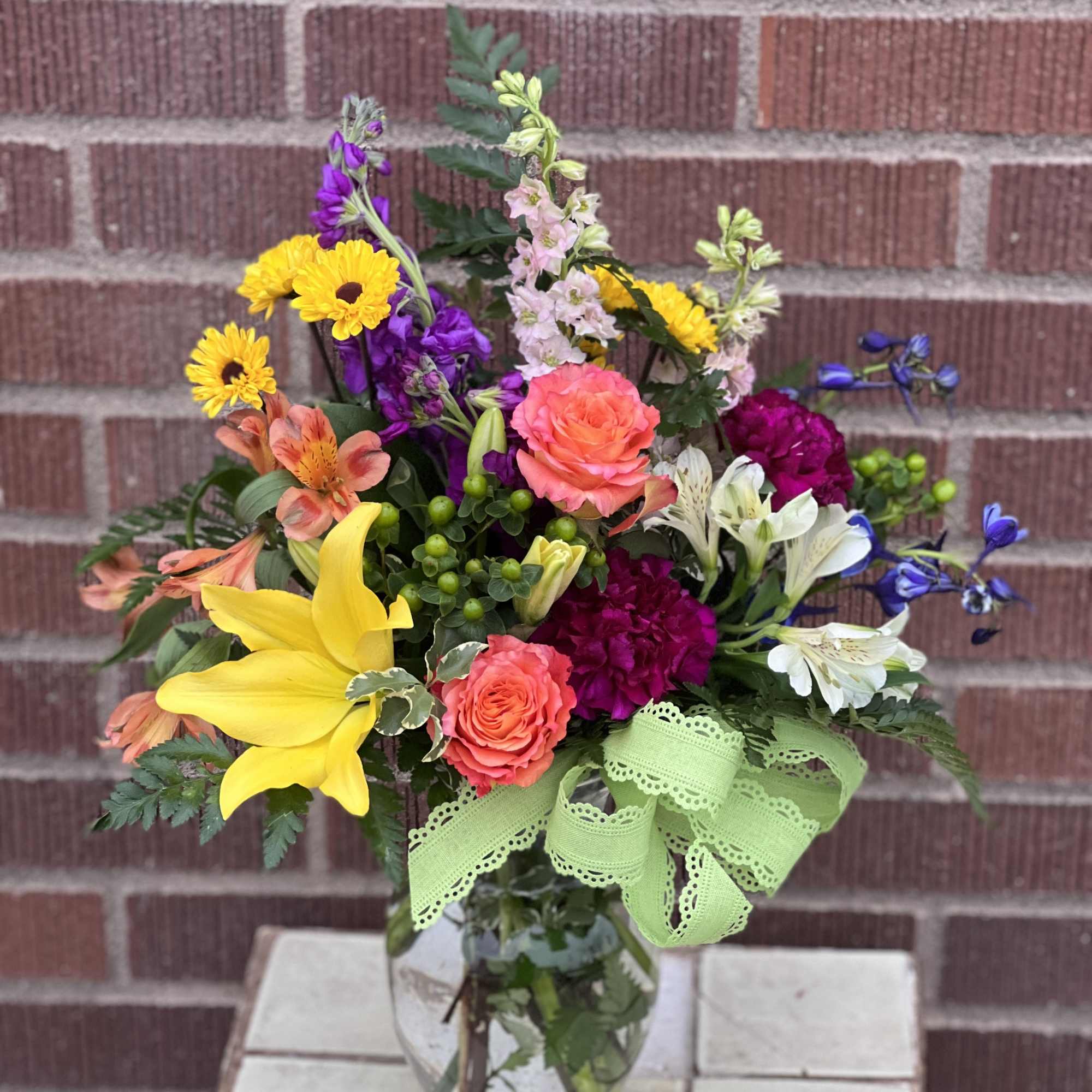 Mixed bouquet in a glass vase with yellow lilies and bright roses