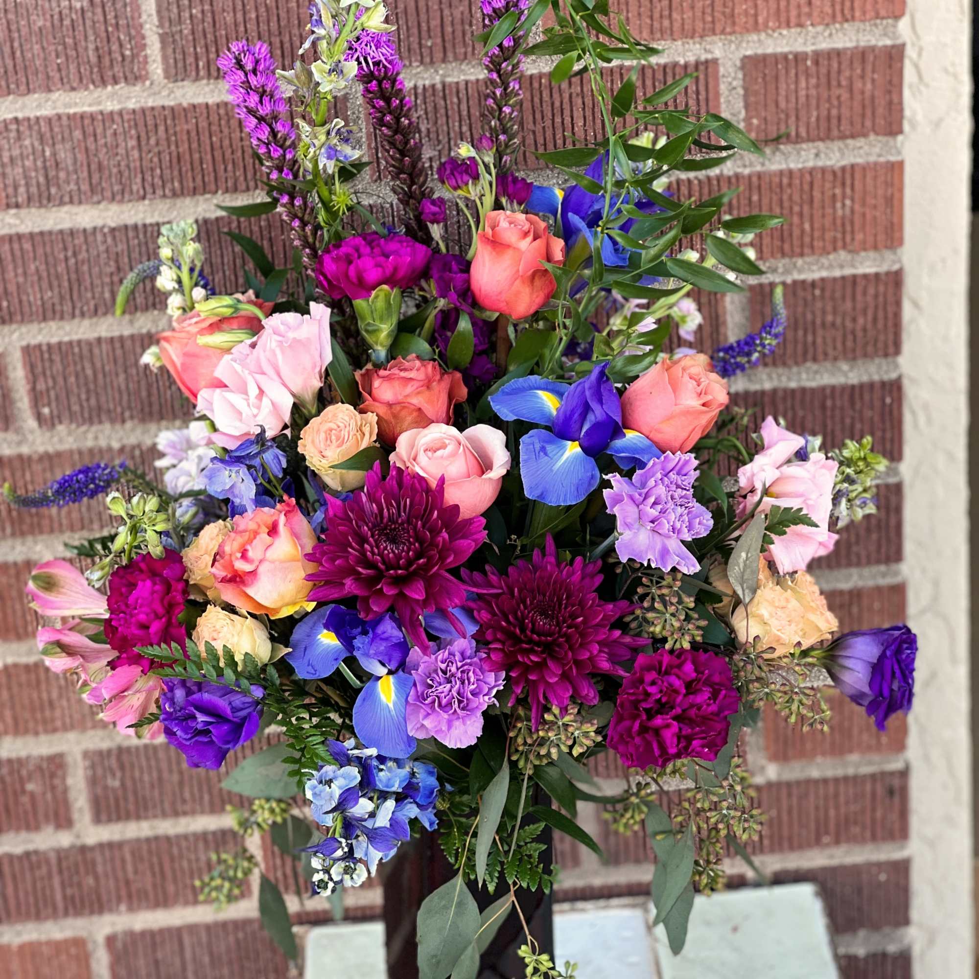 Mixed bouquet with roses, irises, and purple blooms in a vase