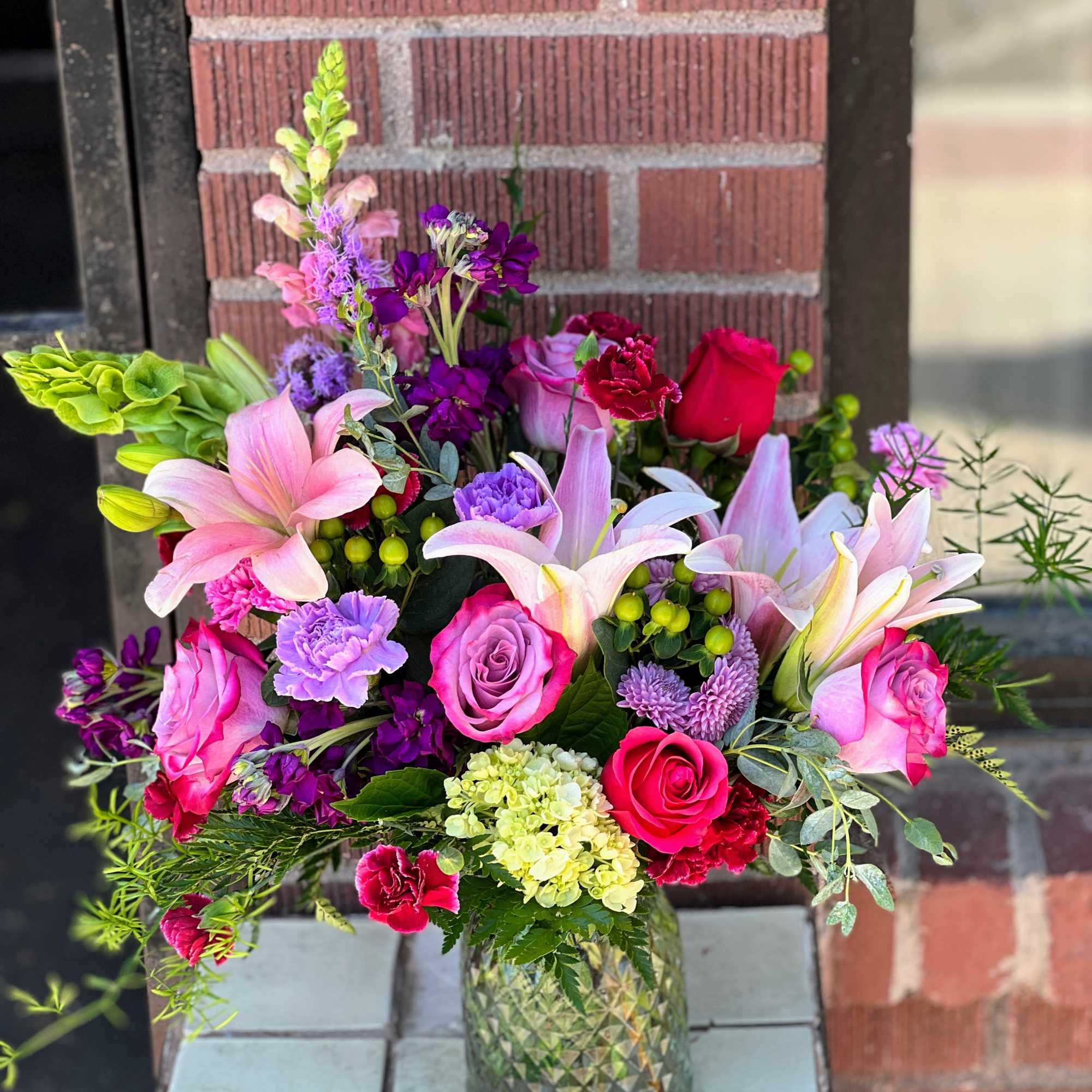Mixed bouquet of pink and purple flowers in a glass vase