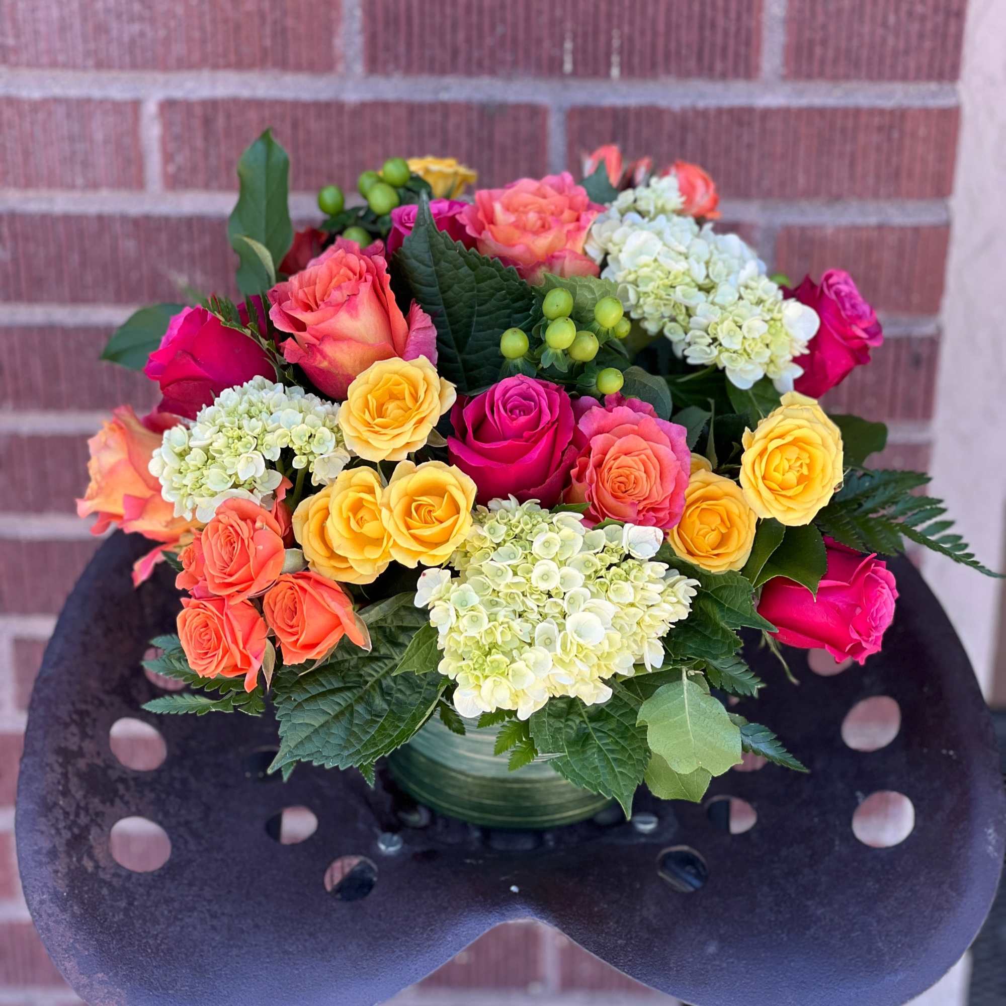 Colorful bouquet of roses and hydrangeas in a green vase