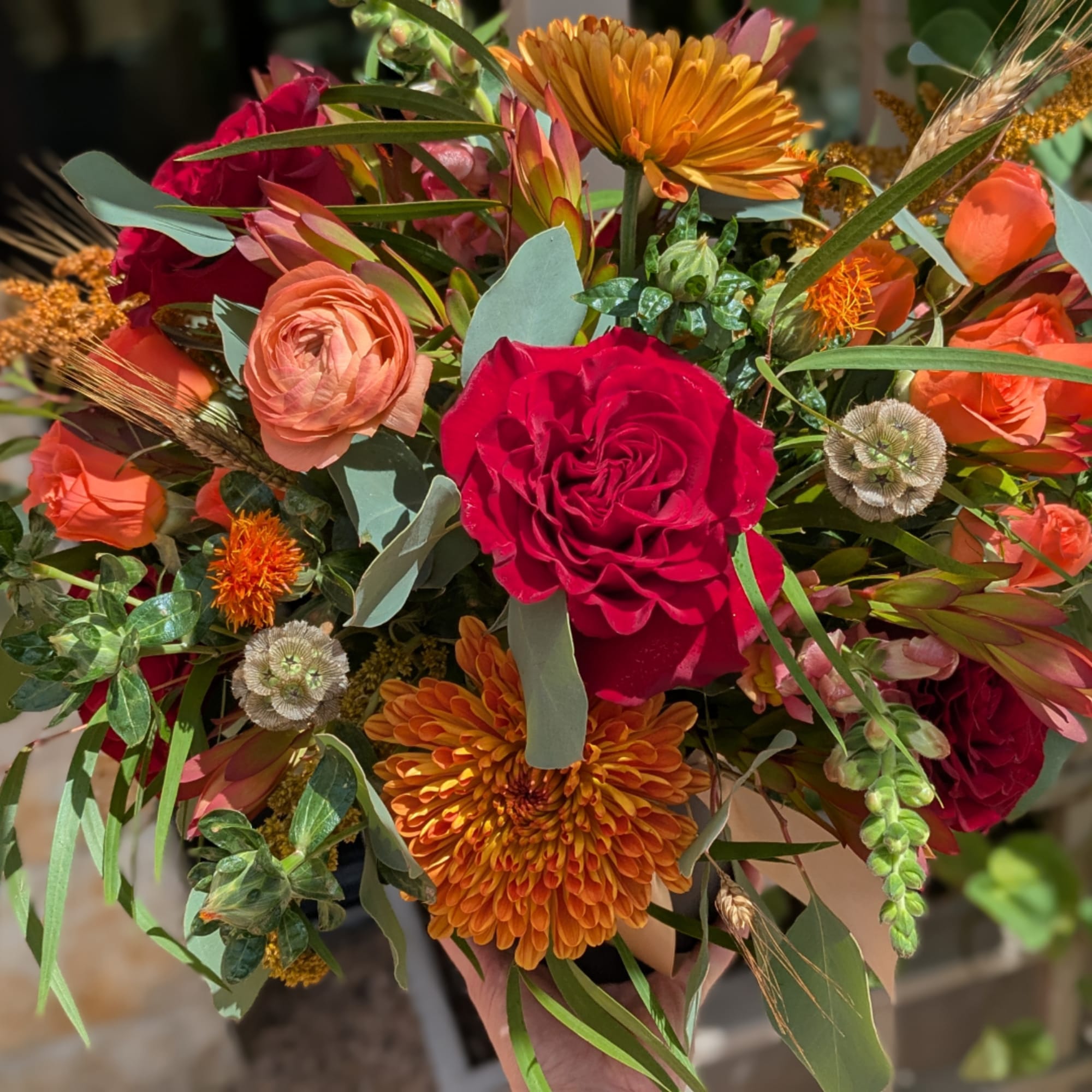 Bouquet of red, orange, and peach flowers with mixed greenery
