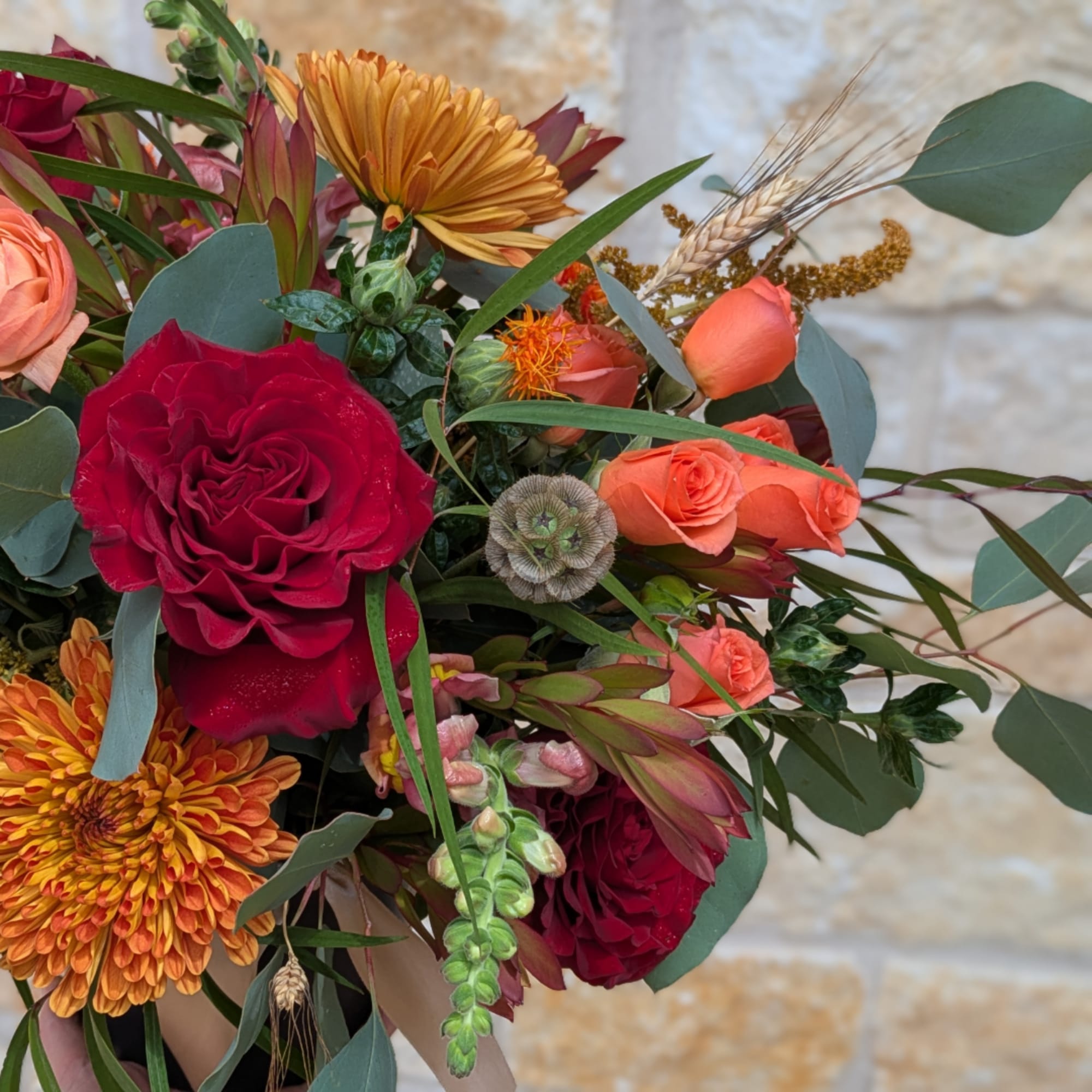 Bouquet of red and orange roses with orange chrysanthemums and greenery
