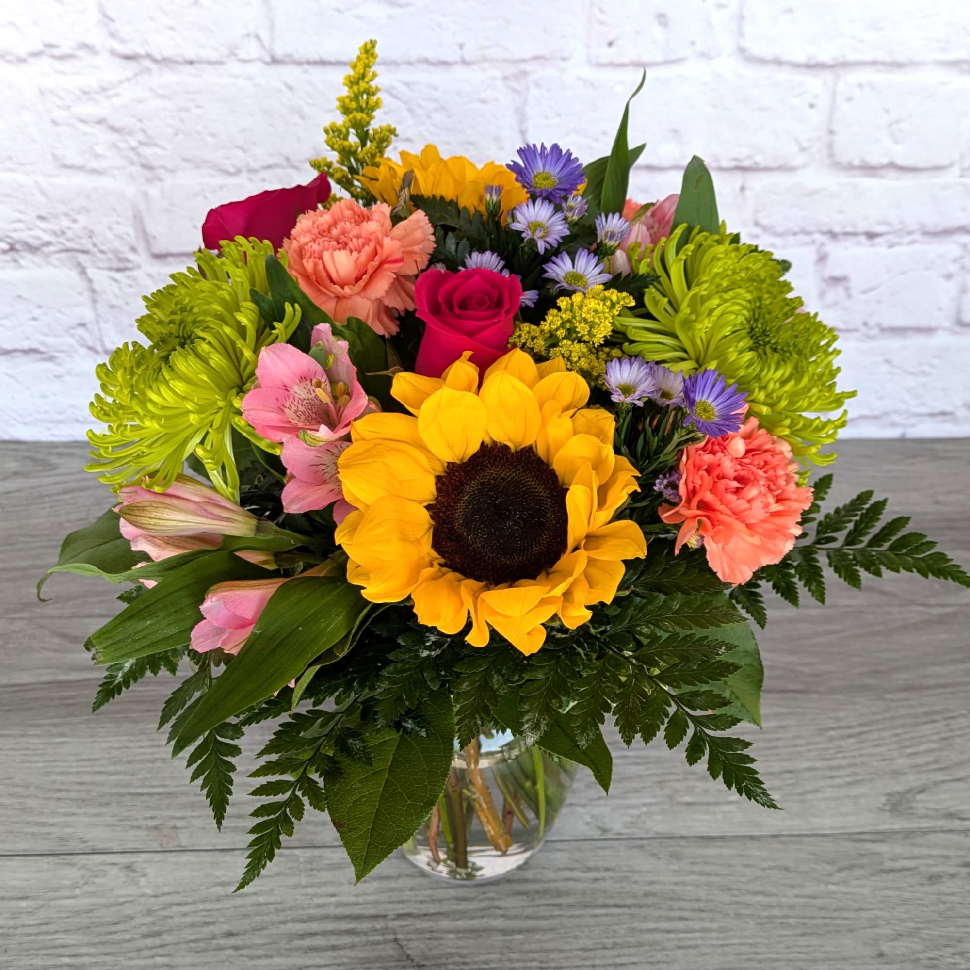 Colorful mixed bouquet with a sunflower in a glass vase