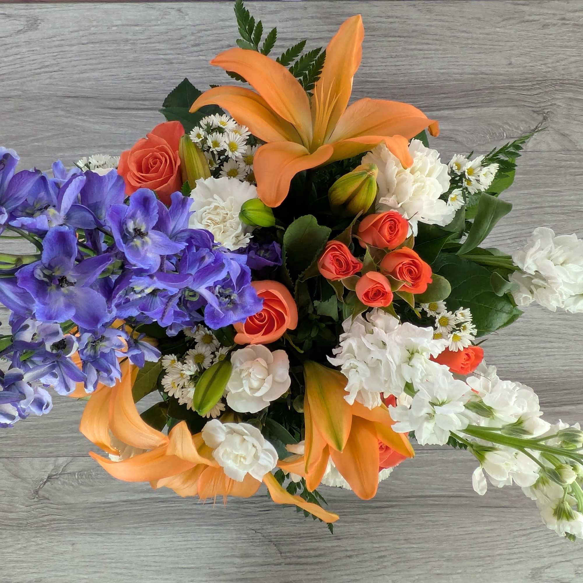 Mixed bouquet with orange lilies, purple flowers, and coral roses
