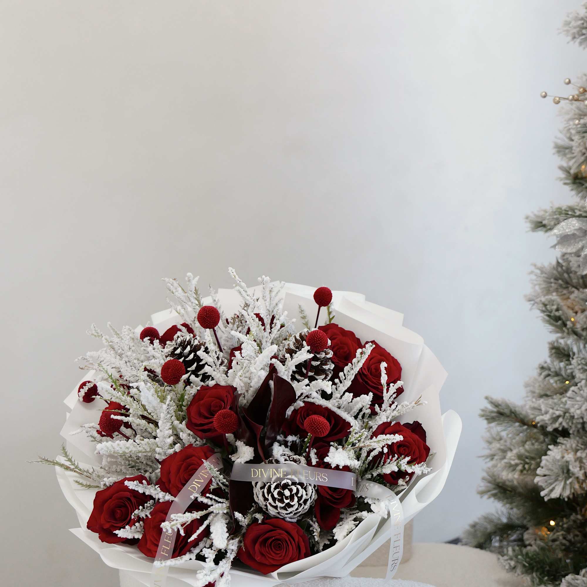 Bouquet of red roses with frosted white accents and pinecones