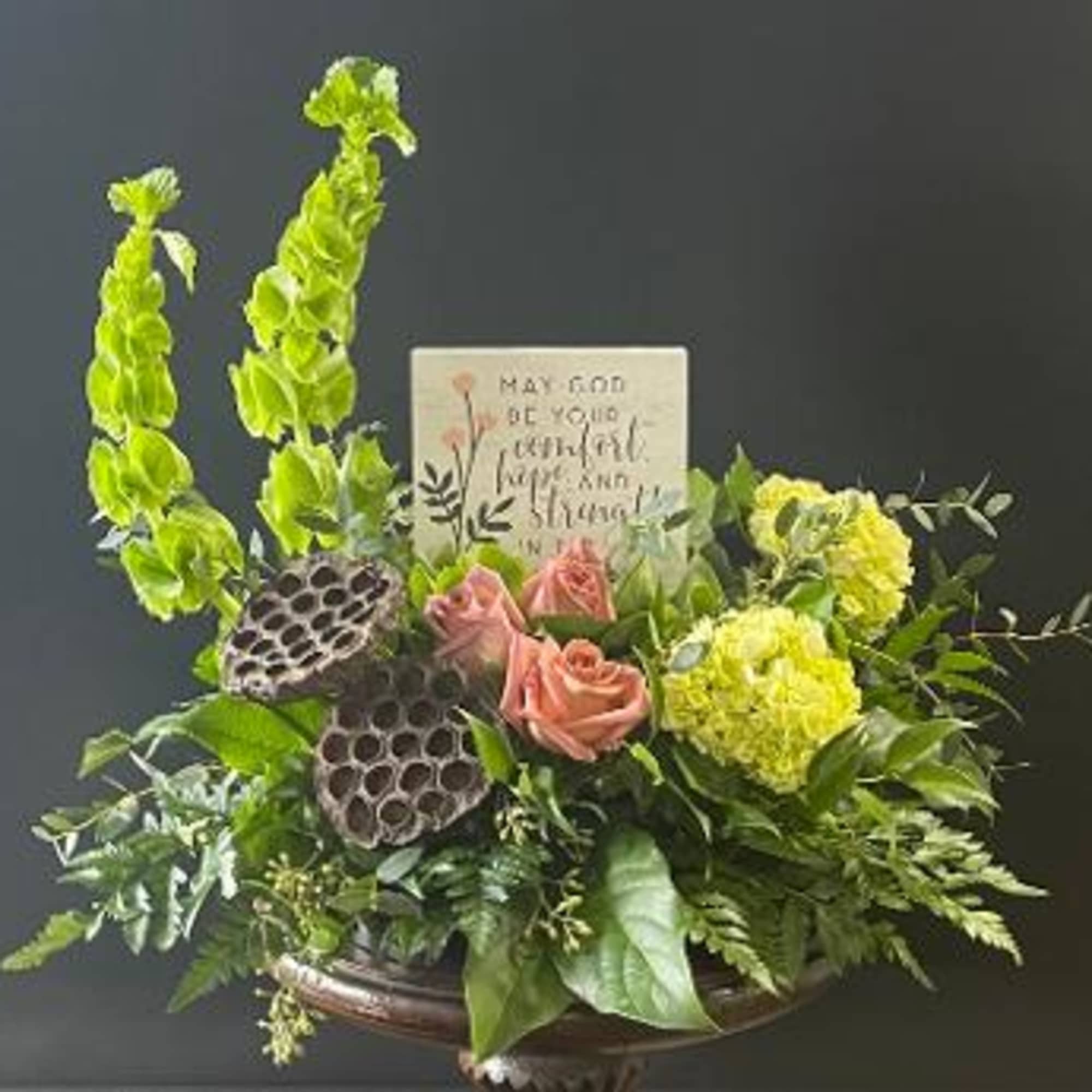 Arrangement of pink roses and yellow flowers with tall green blooms in a vase