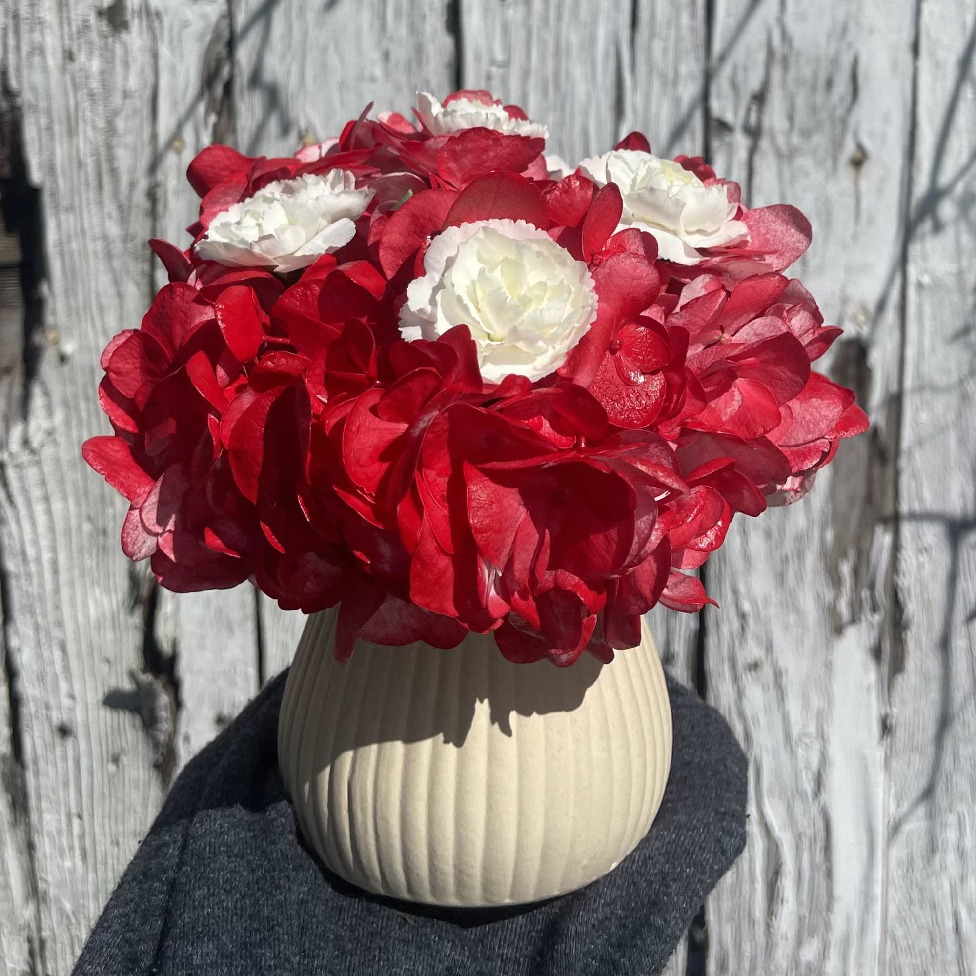 Red and white flower arrangement in a beige ribbed vase