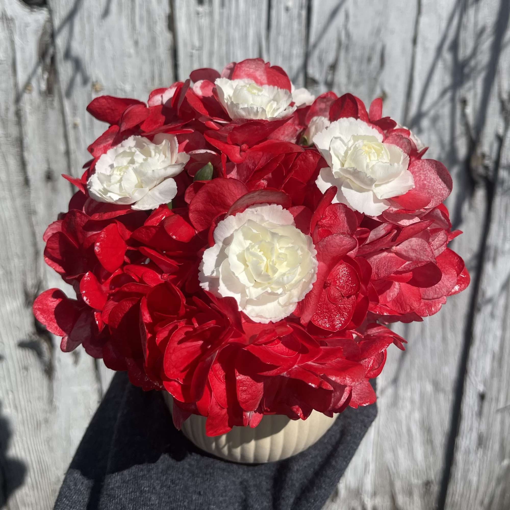 Red and white flower arrangement in a cream vase