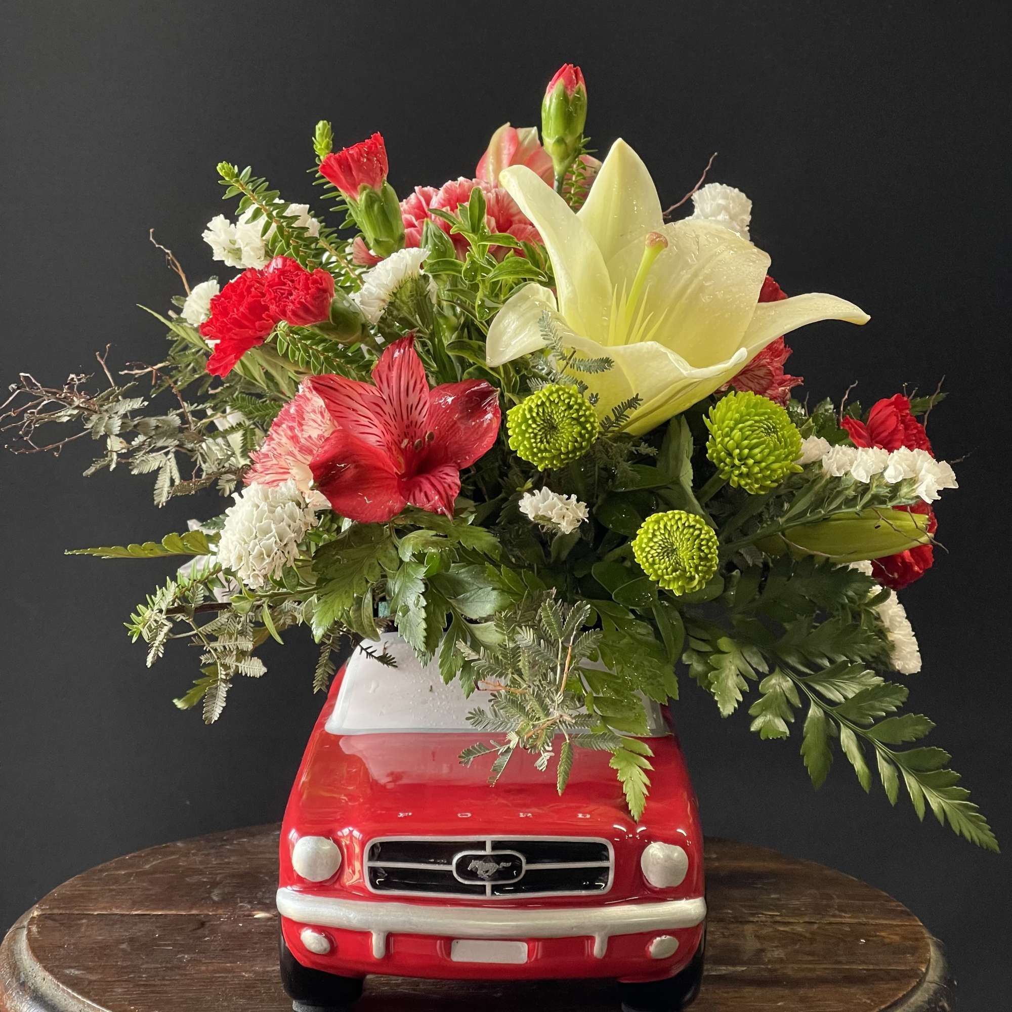 Red truck planter filled with mixed flowers and a white lily