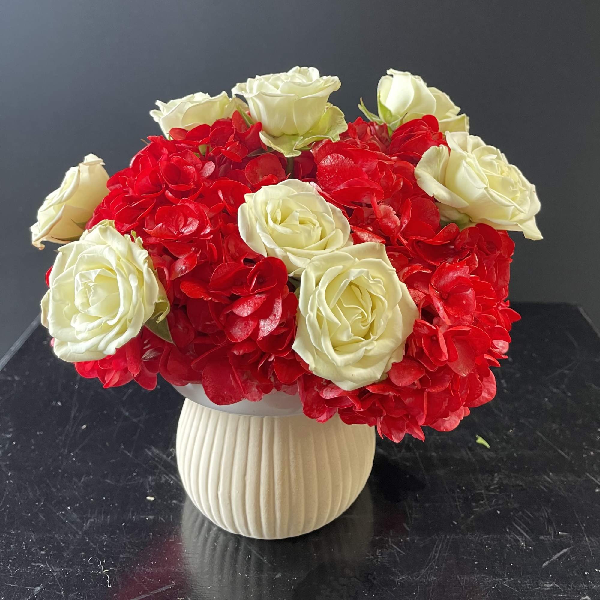 Red and white roses arranged in a cream vase