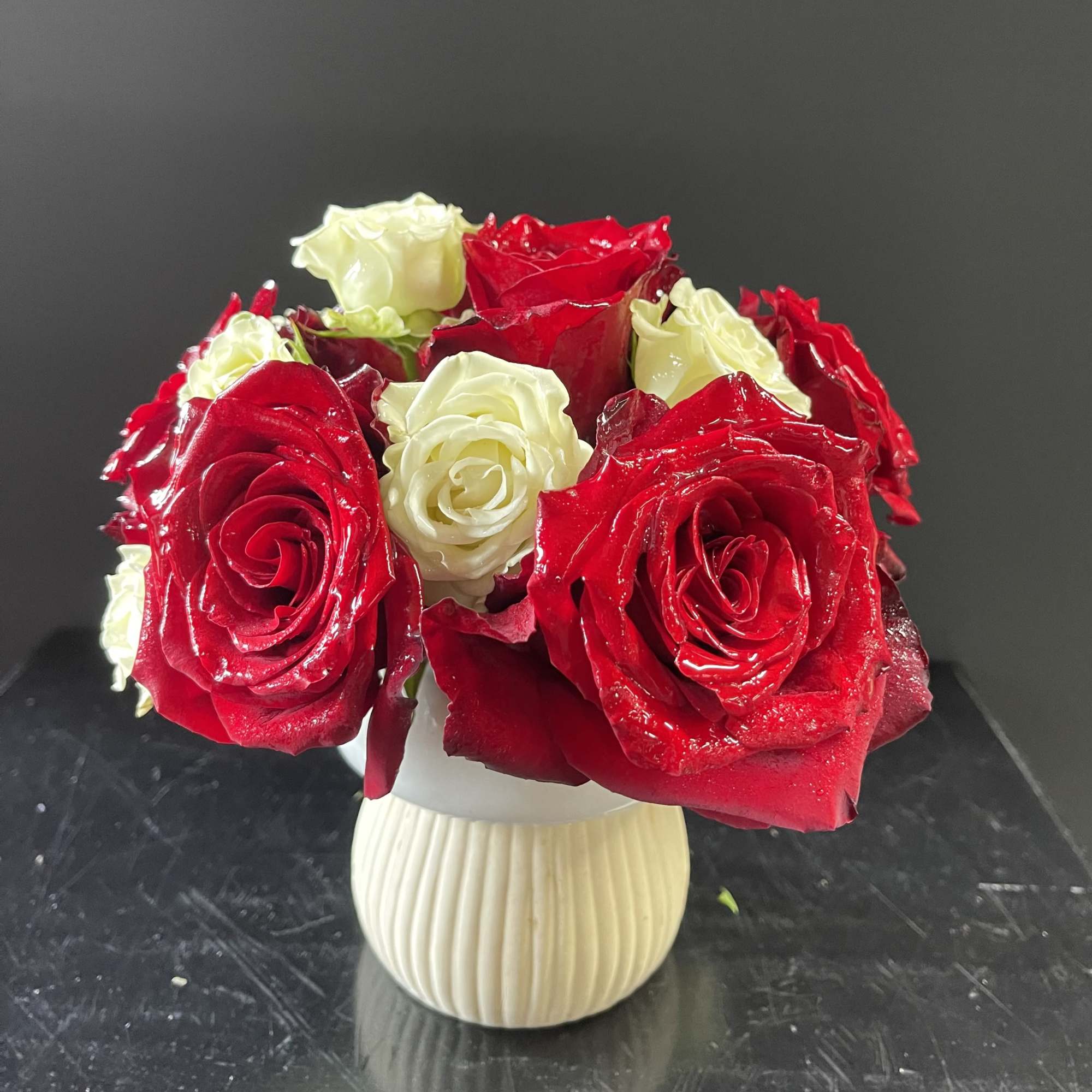 Red and white roses arranged in a small cream vase