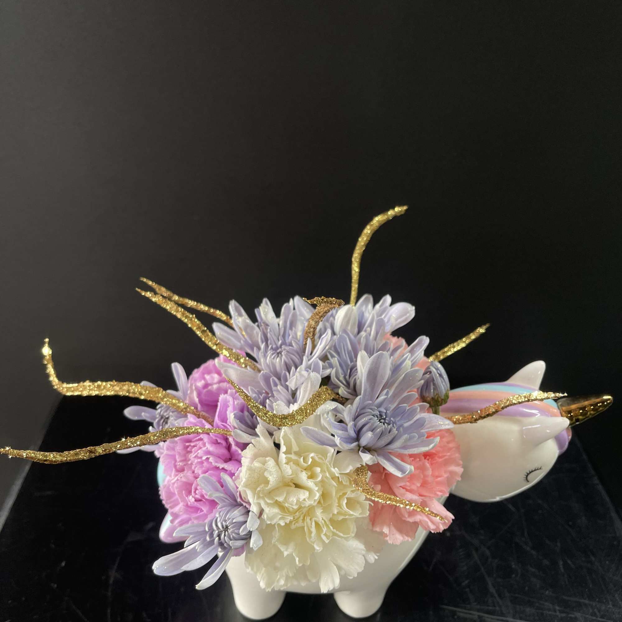 Pastel flower arrangement in a white unicorn-shaped container