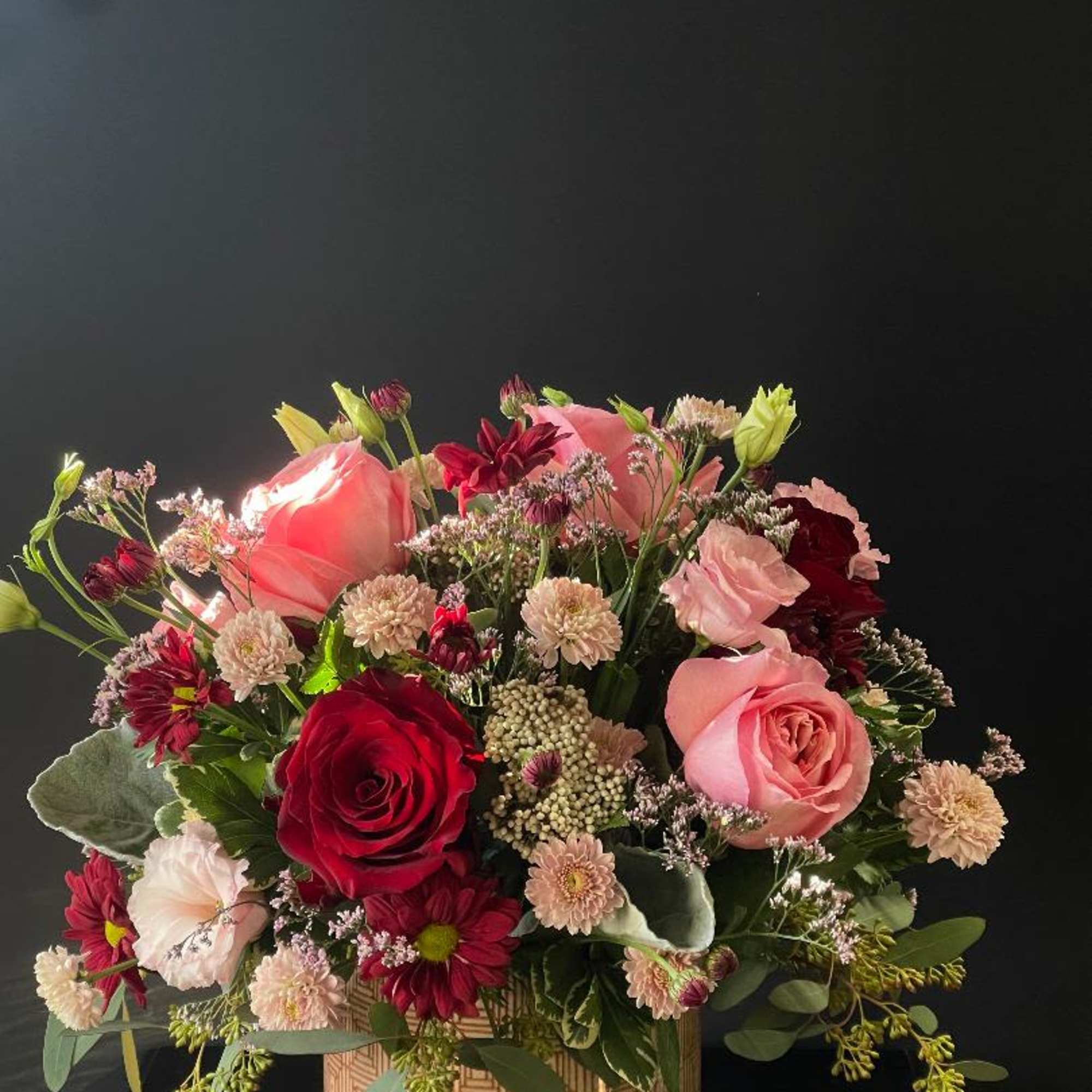 Mixed bouquet of pink and red roses in a patterned box
