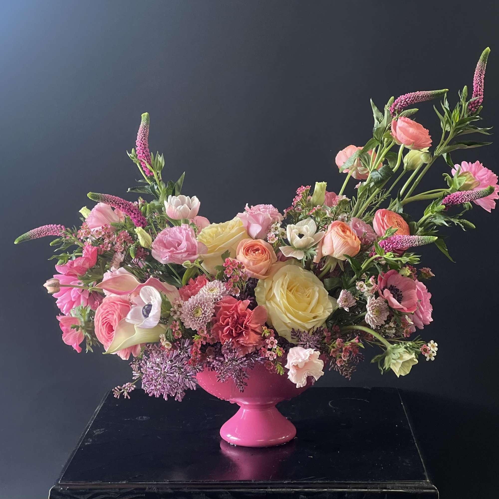 Pink and yellow mixed flower arrangement in a bright pink vase