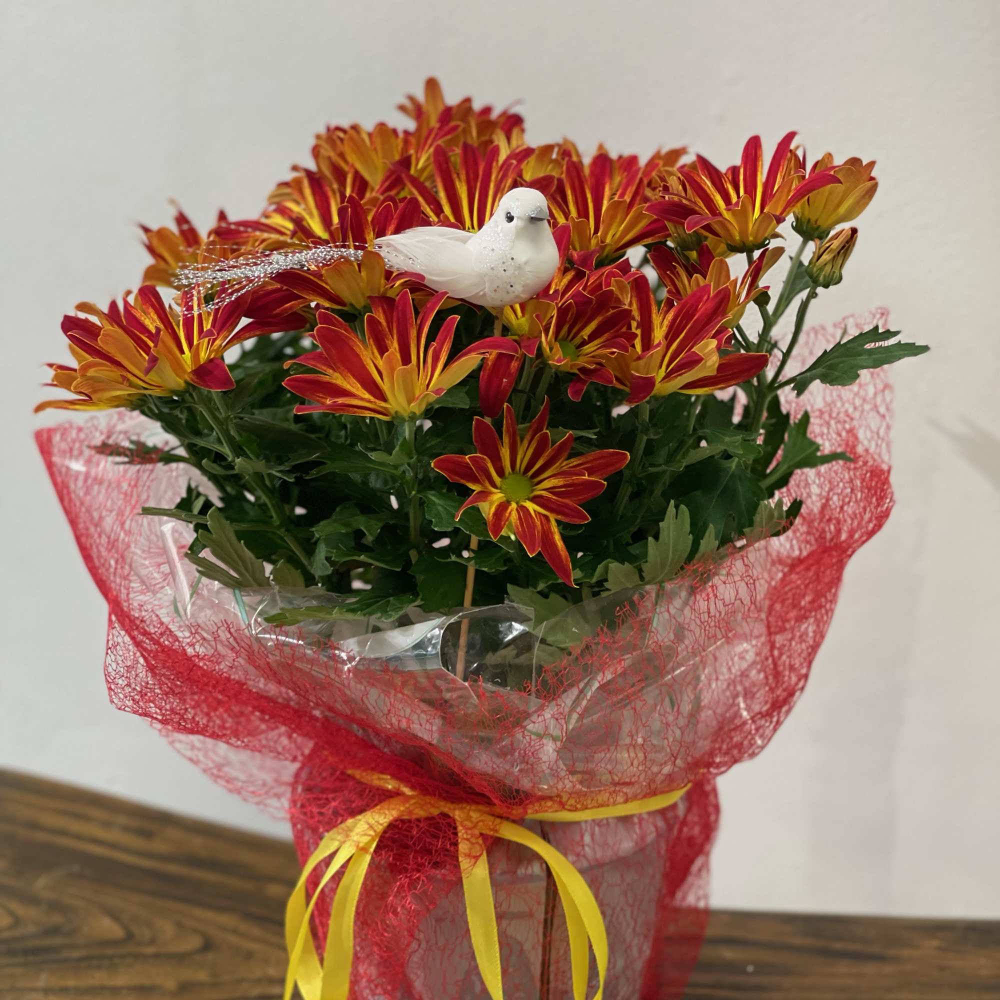 Bouquet of red and yellow daisies with a white bird decoration