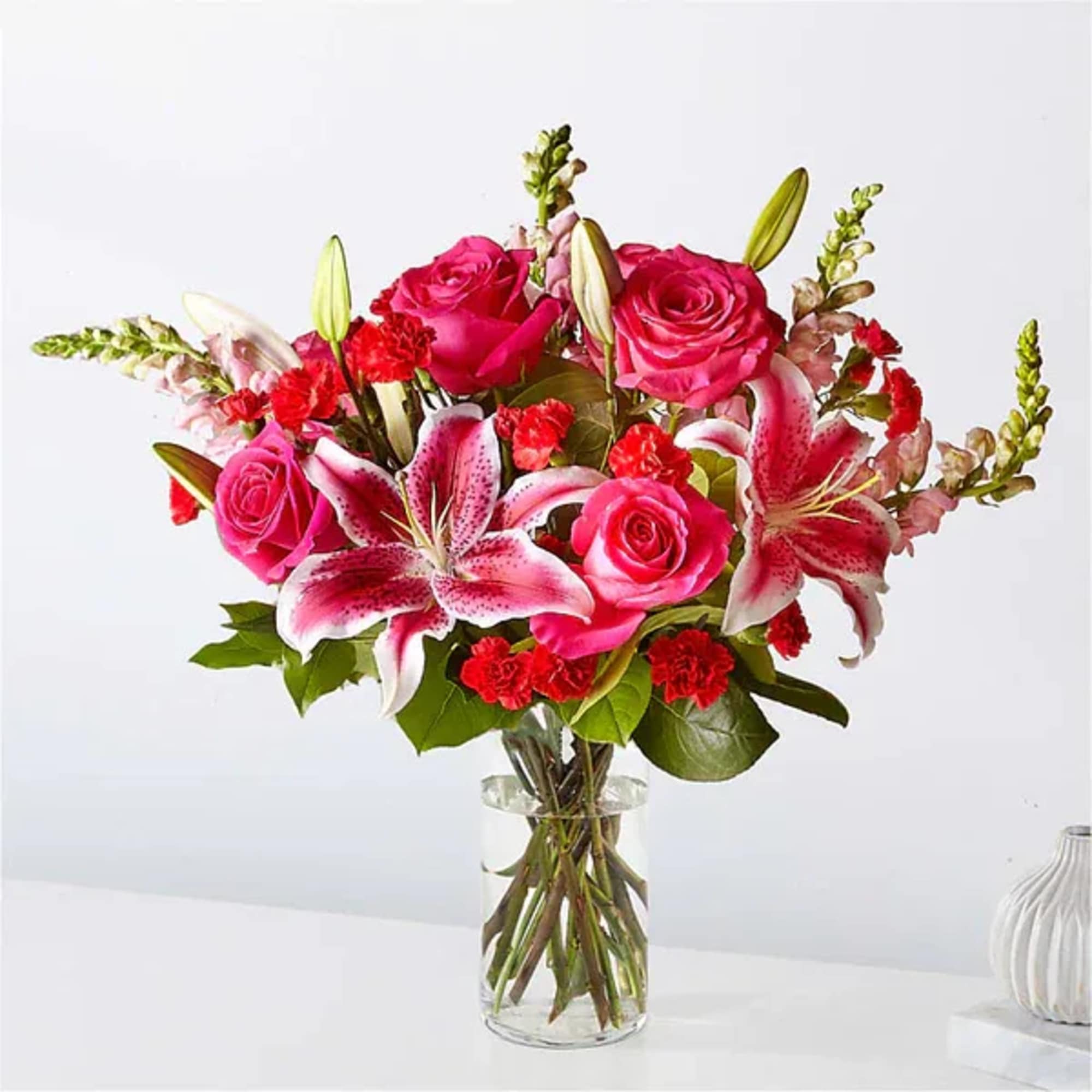 Pink roses and lilies arranged in a clear glass vase