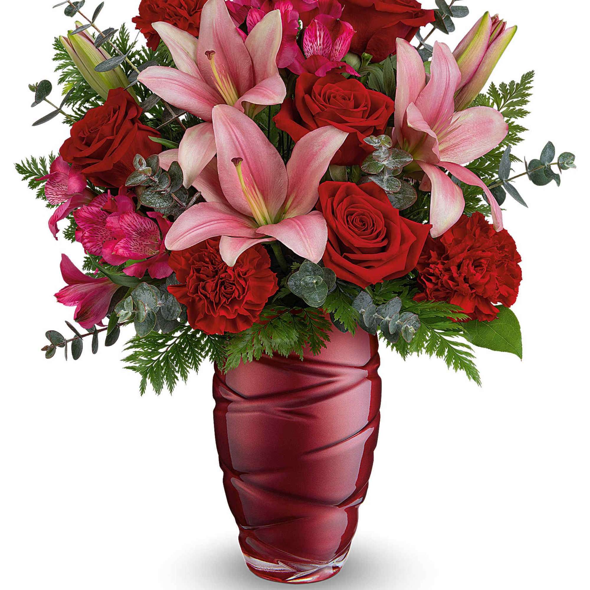 Bouquet of red roses and pink lilies in a red glass vase
