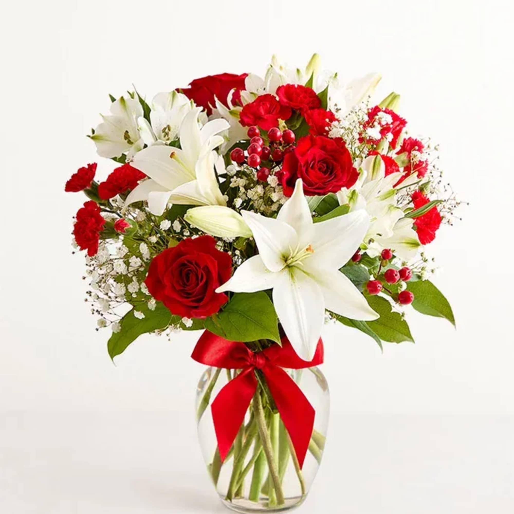 Red roses and white lilies in a glass vase with a red ribbon