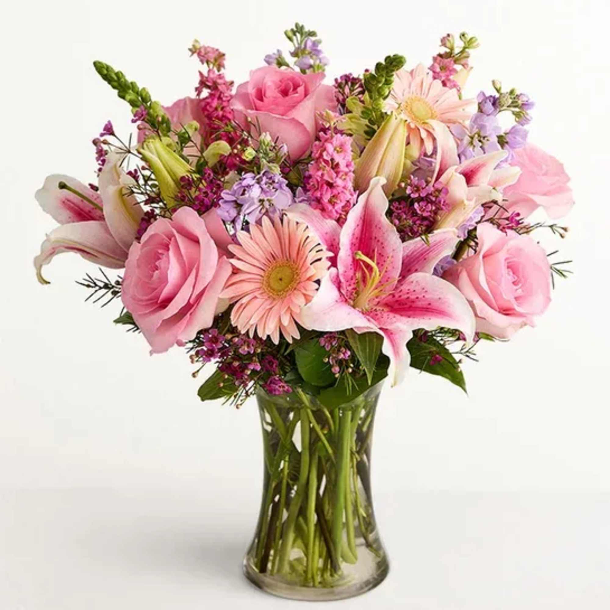 Pink roses, lilies, and daisies in a clear glass vase