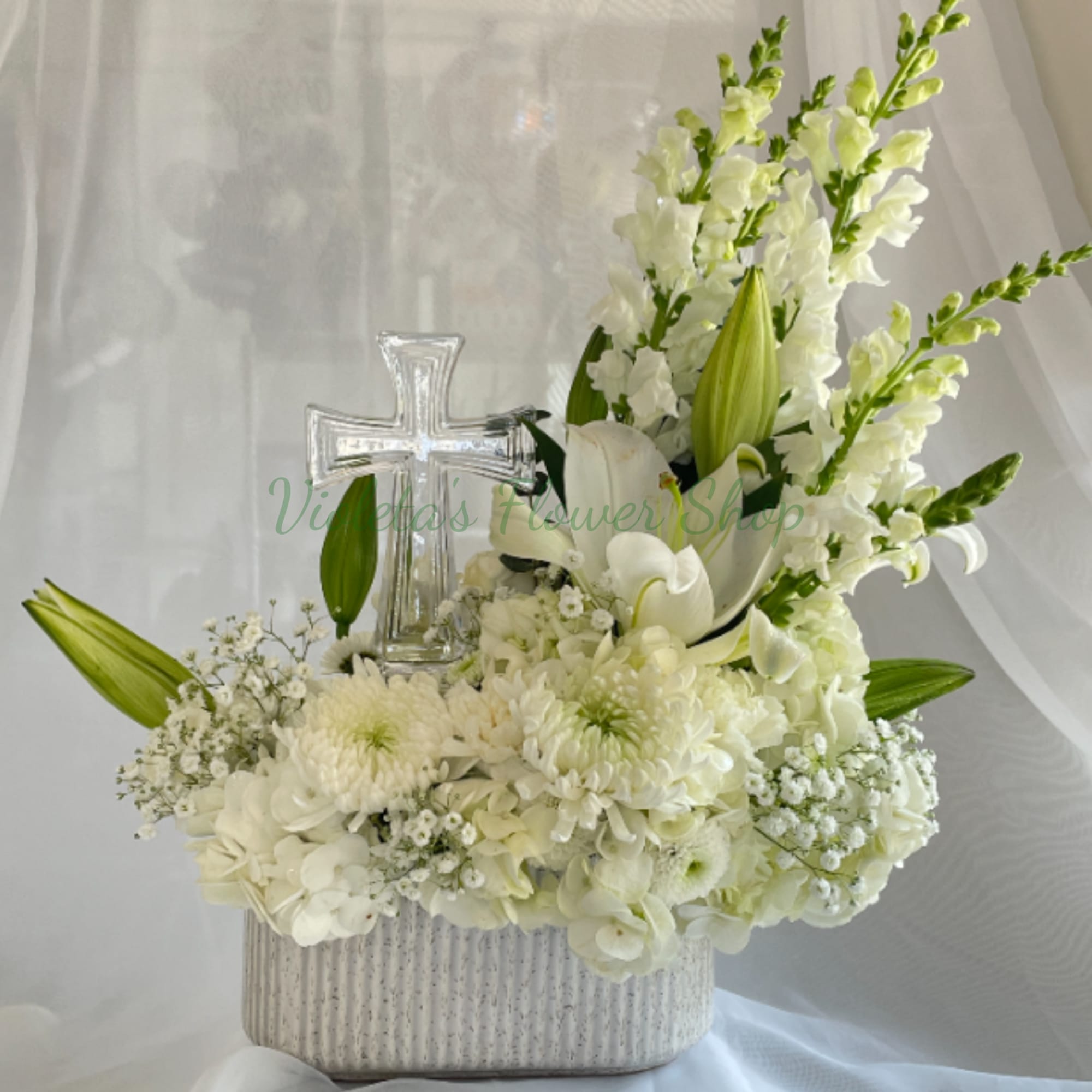 A serene, upright sympathy arrangement centered on pure white lilies and a