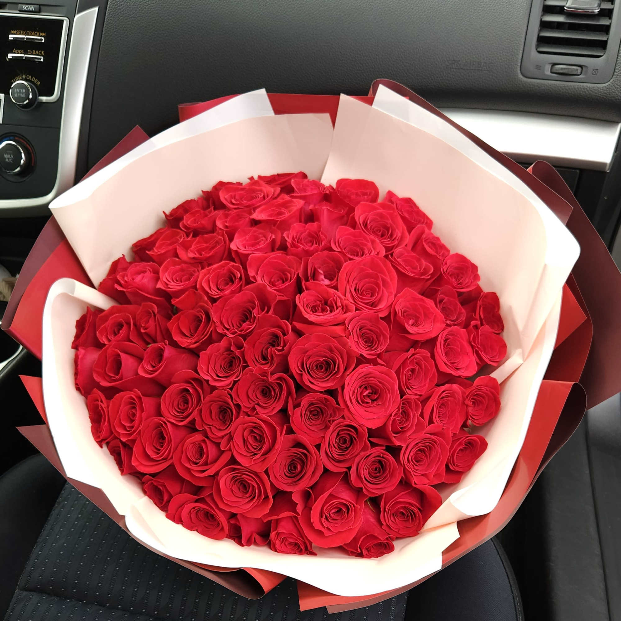 Large bouquet of red roses wrapped in white and red paper