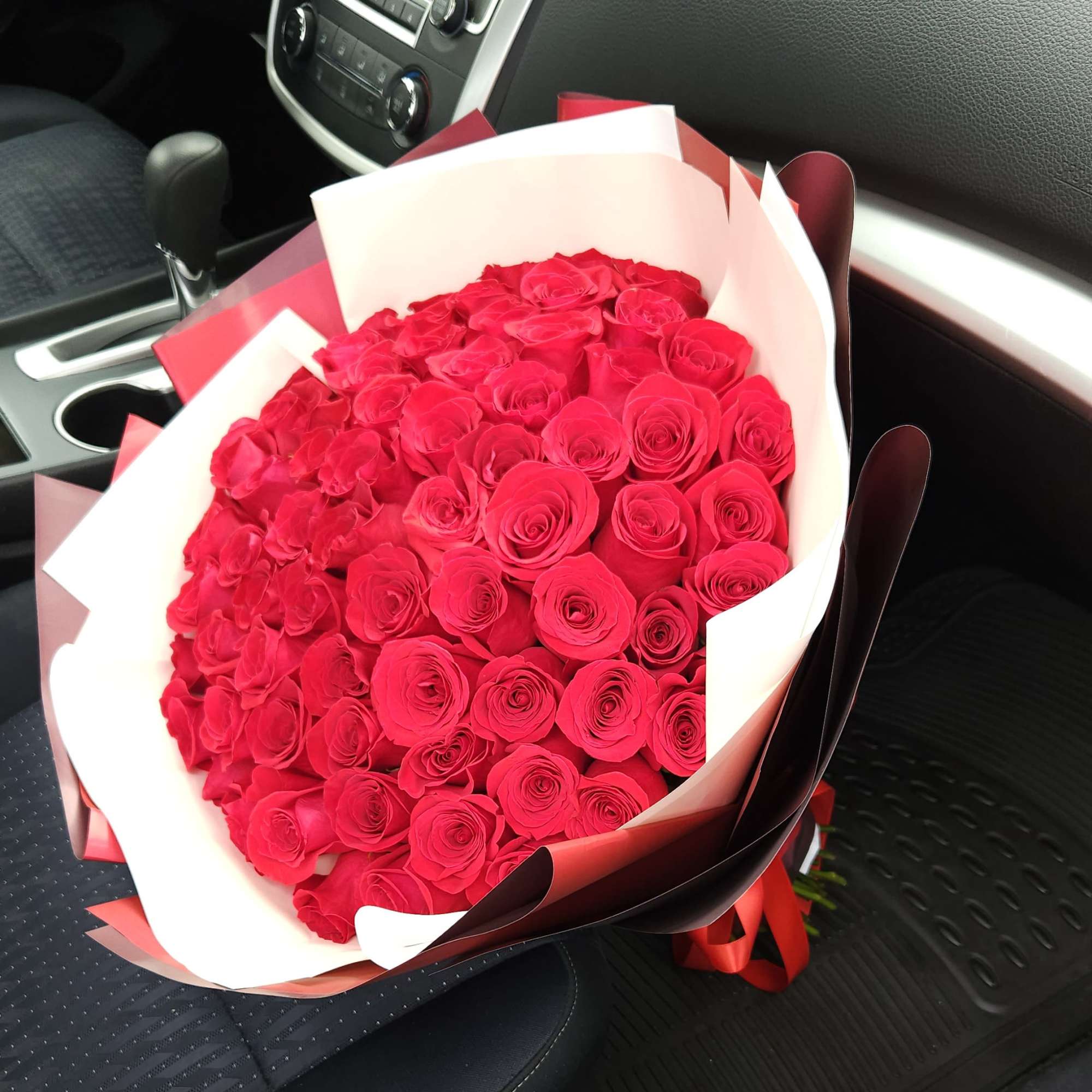 Large bouquet of red roses wrapped in white and burgundy paper