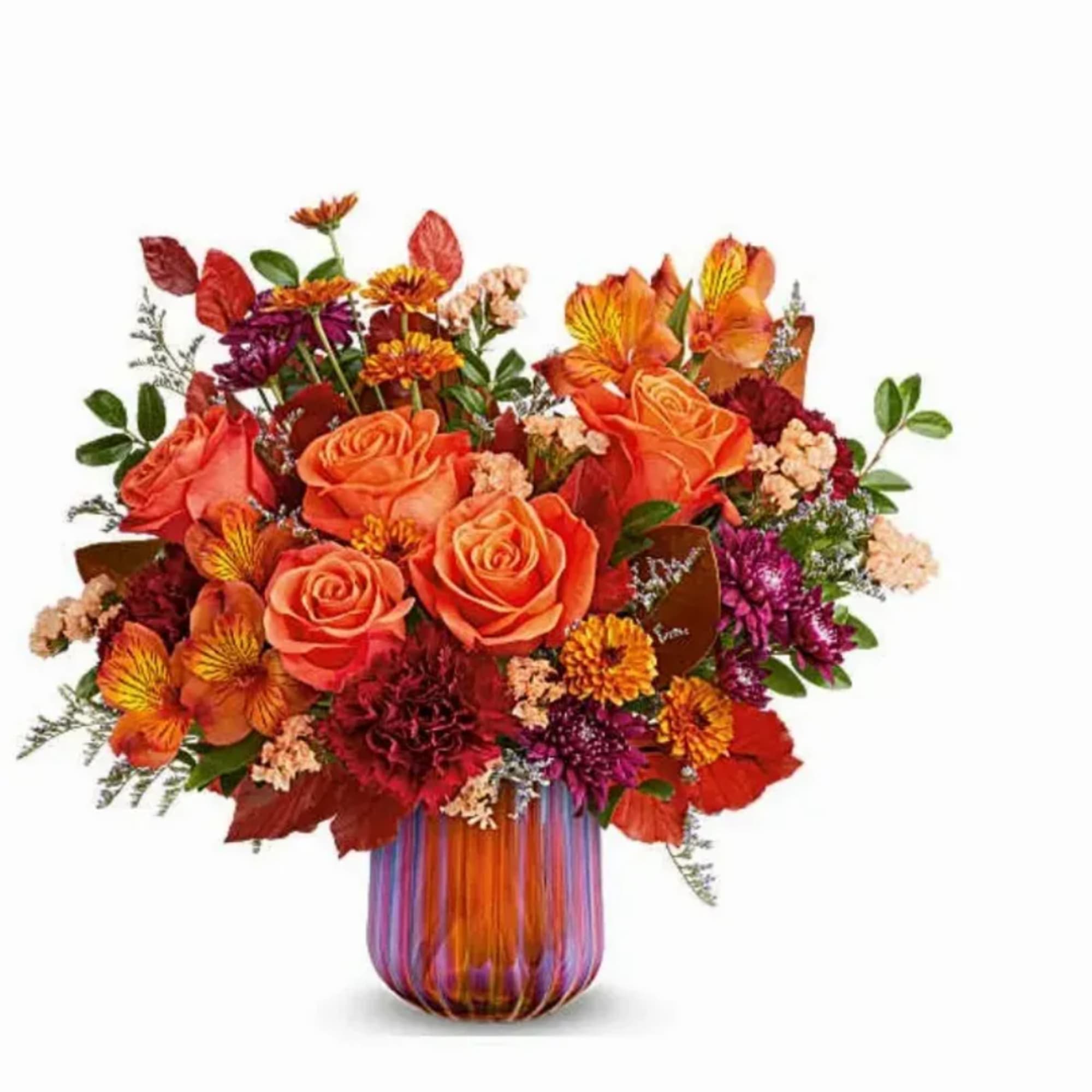 Orange and red mixed bouquet in a striped glass vase