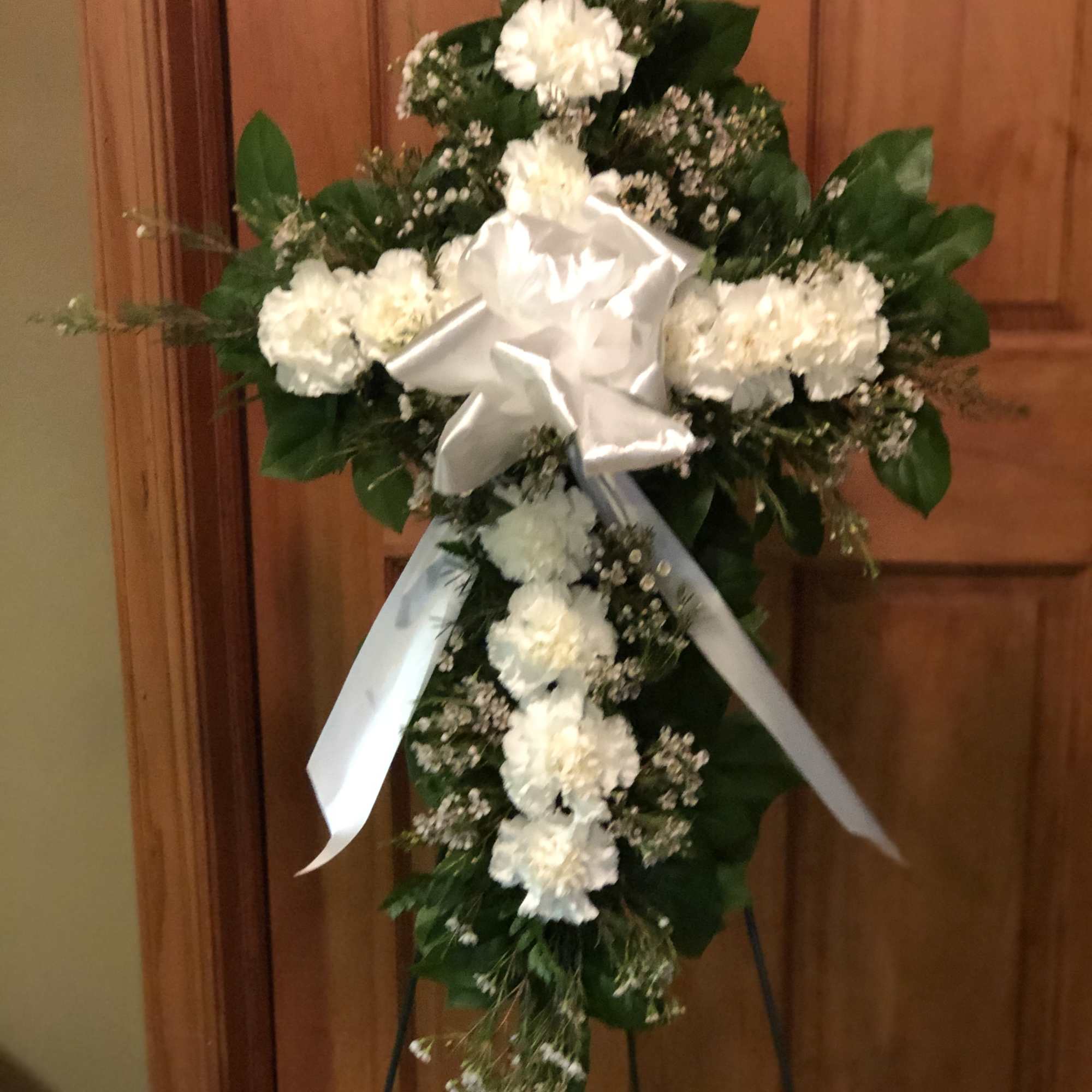 Our Carnation Cross is highlighted with a dozen carnations with greenery and