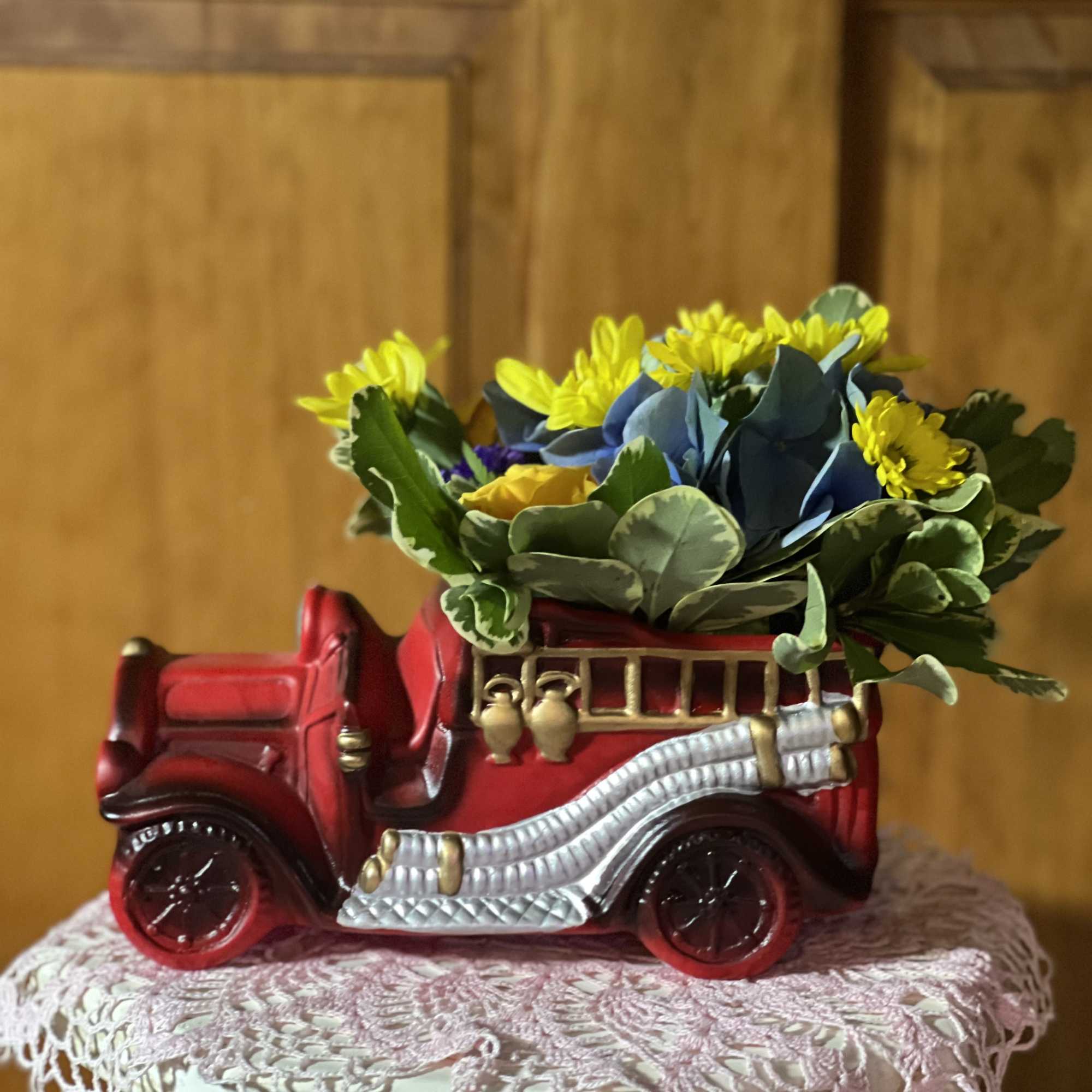 Red vintage truck planter with yellow flowers and blue foliage