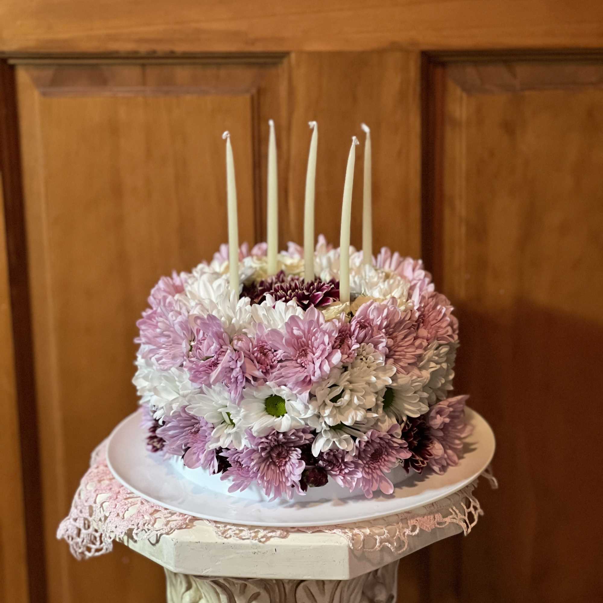 Round pink and white flower cake with five tall candles