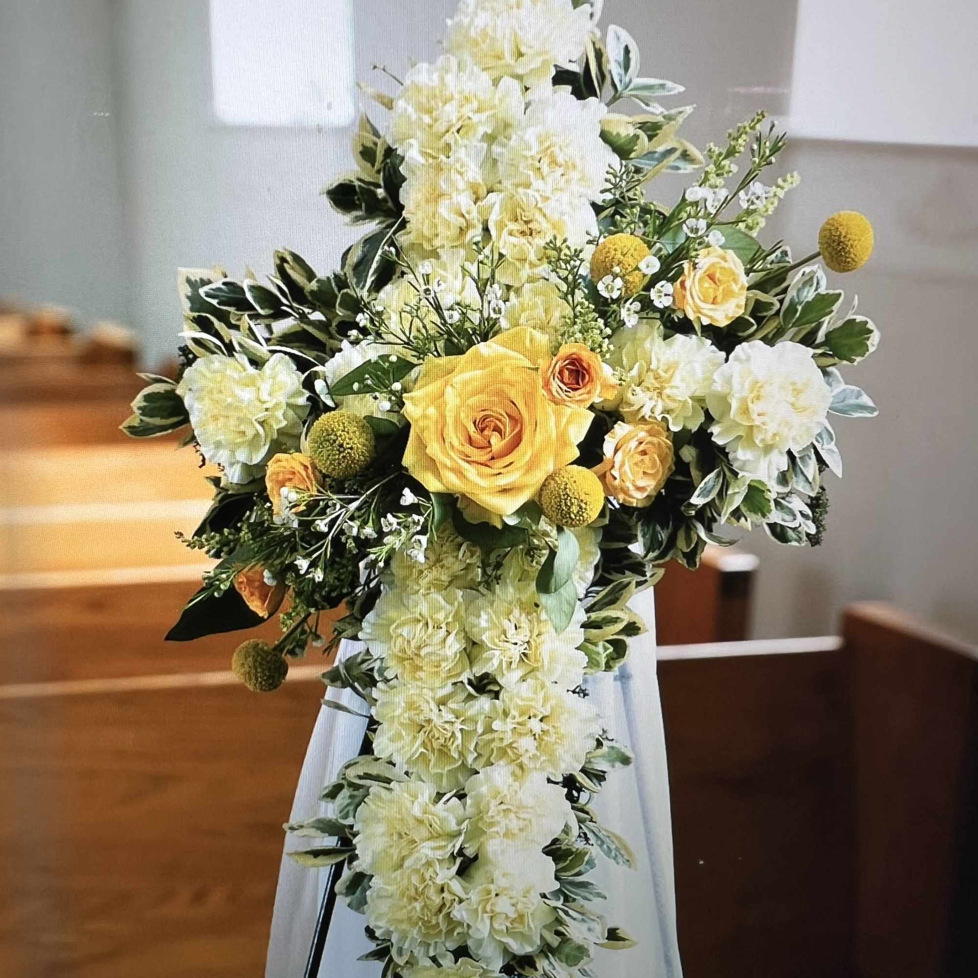 Our Carnation Cross is highlighted with a dozen carnations with greenery and