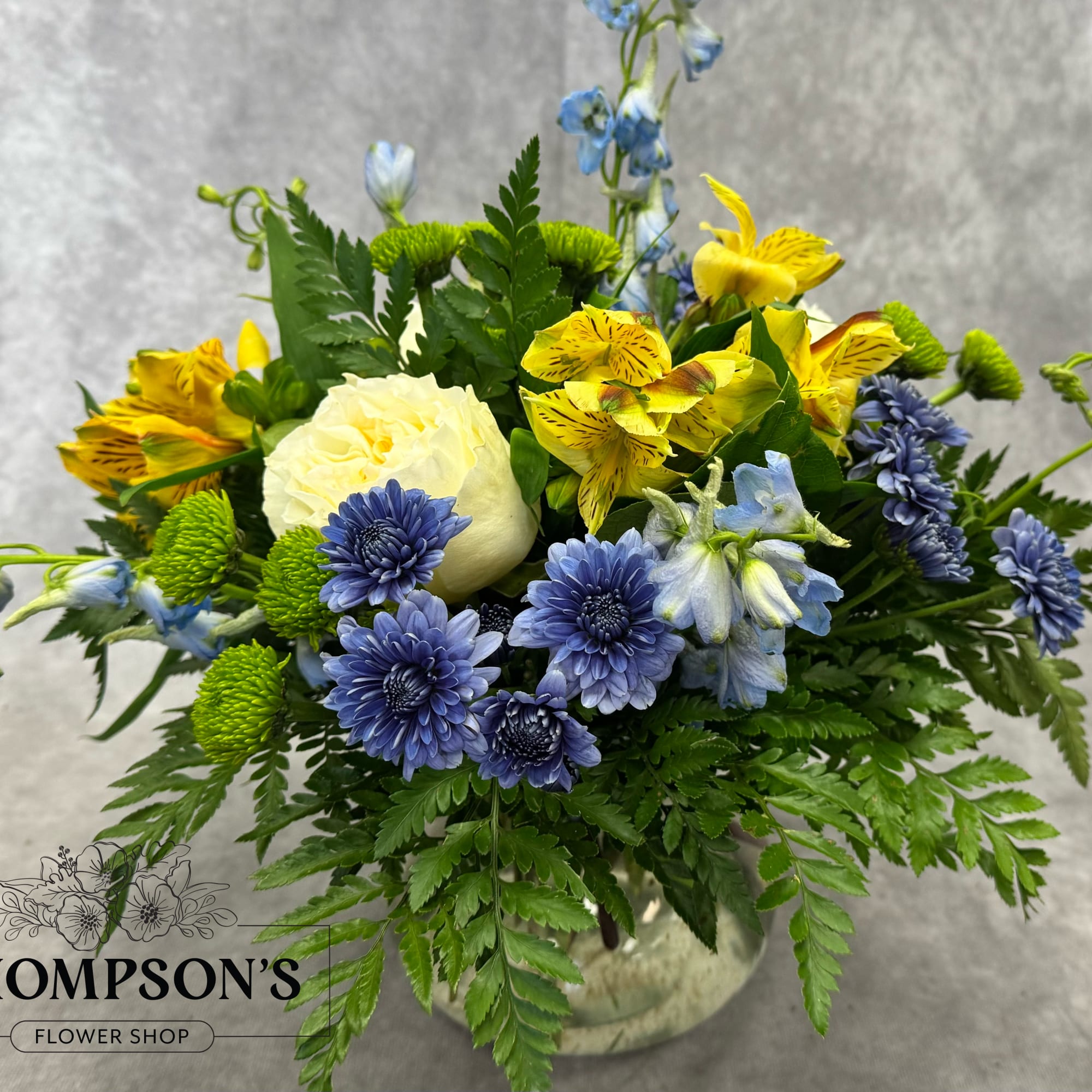Mixed bouquet of yellow, blue, and white flowers in a vase