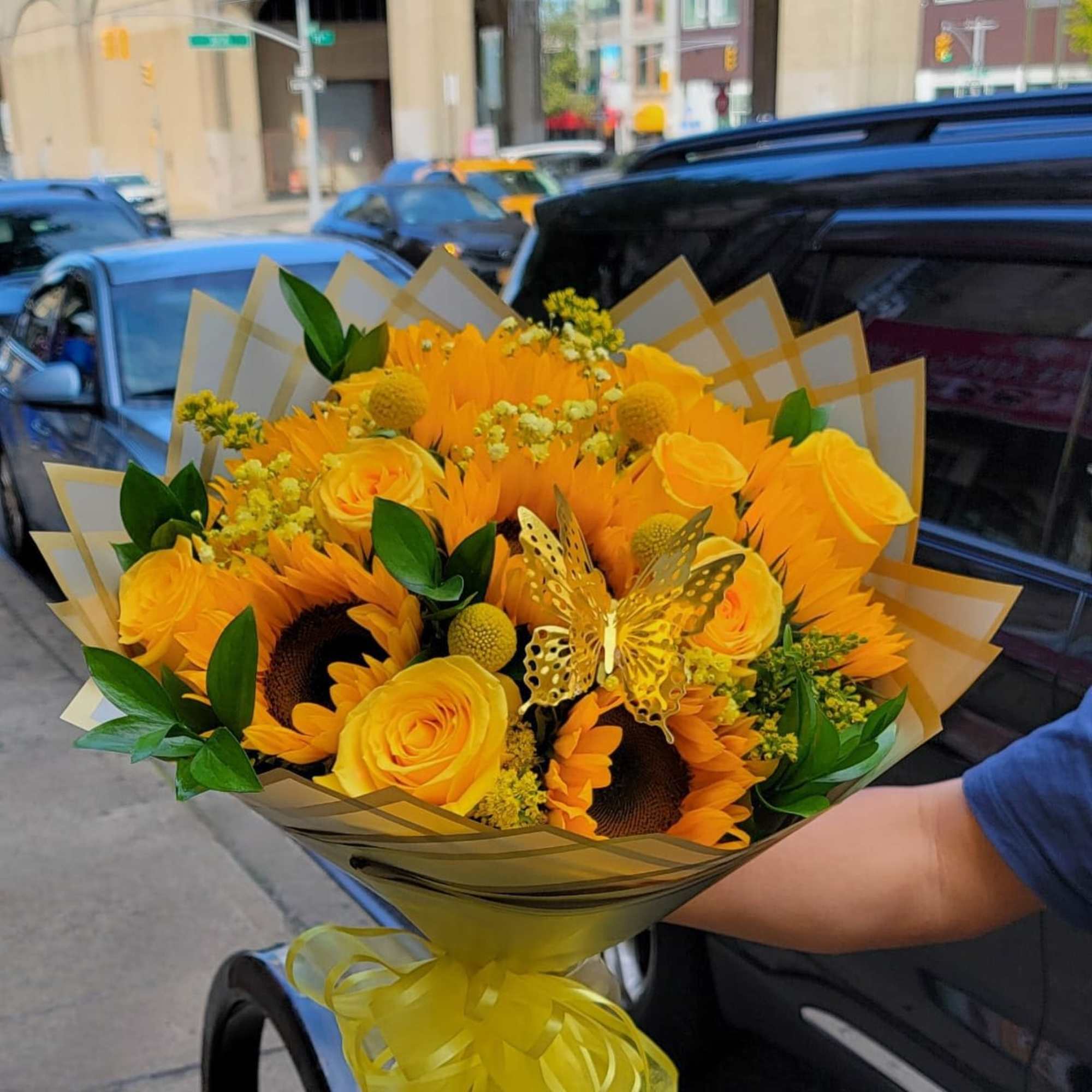 This wonderful wrap bouquet consists of yellow roses, sunflowers, baby breath, and
