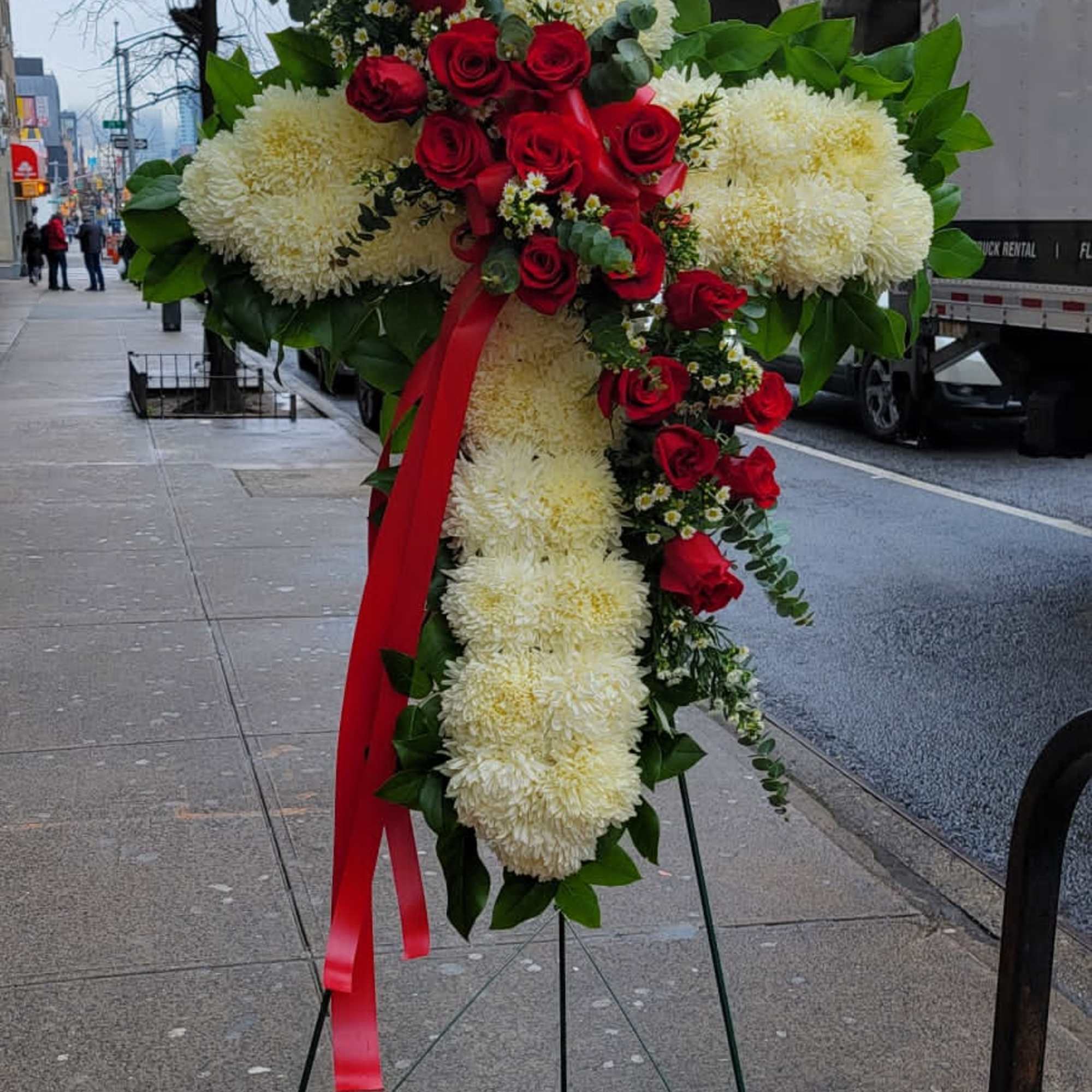 Standing floral cross with red roses and white mums on an easel