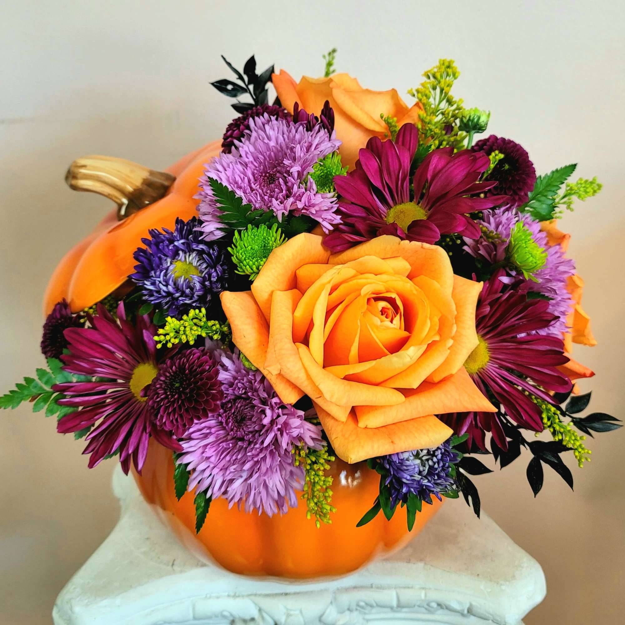 Orange pumpkin vase with orange and purple flowers