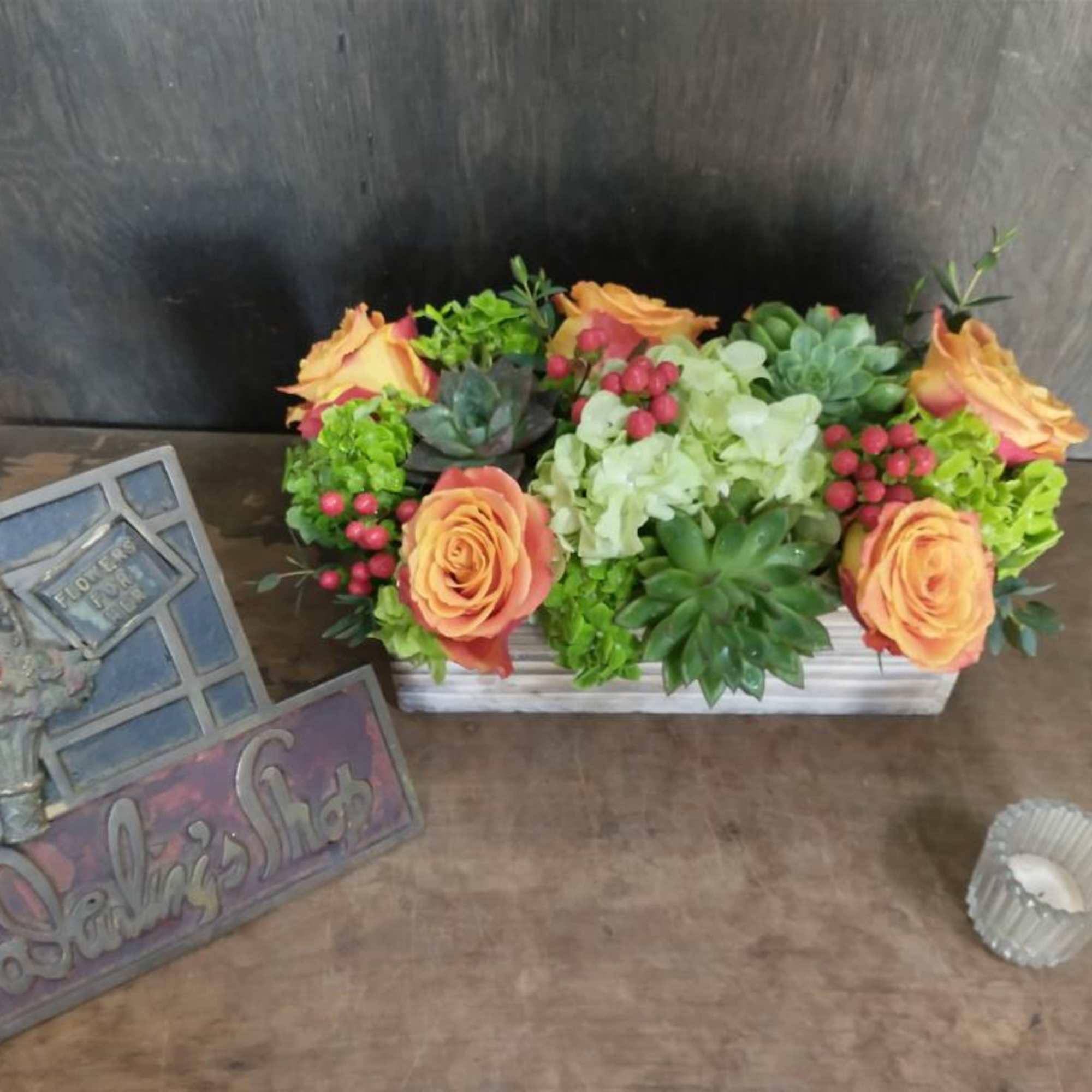 Orange roses and succulents in a rectangular planter