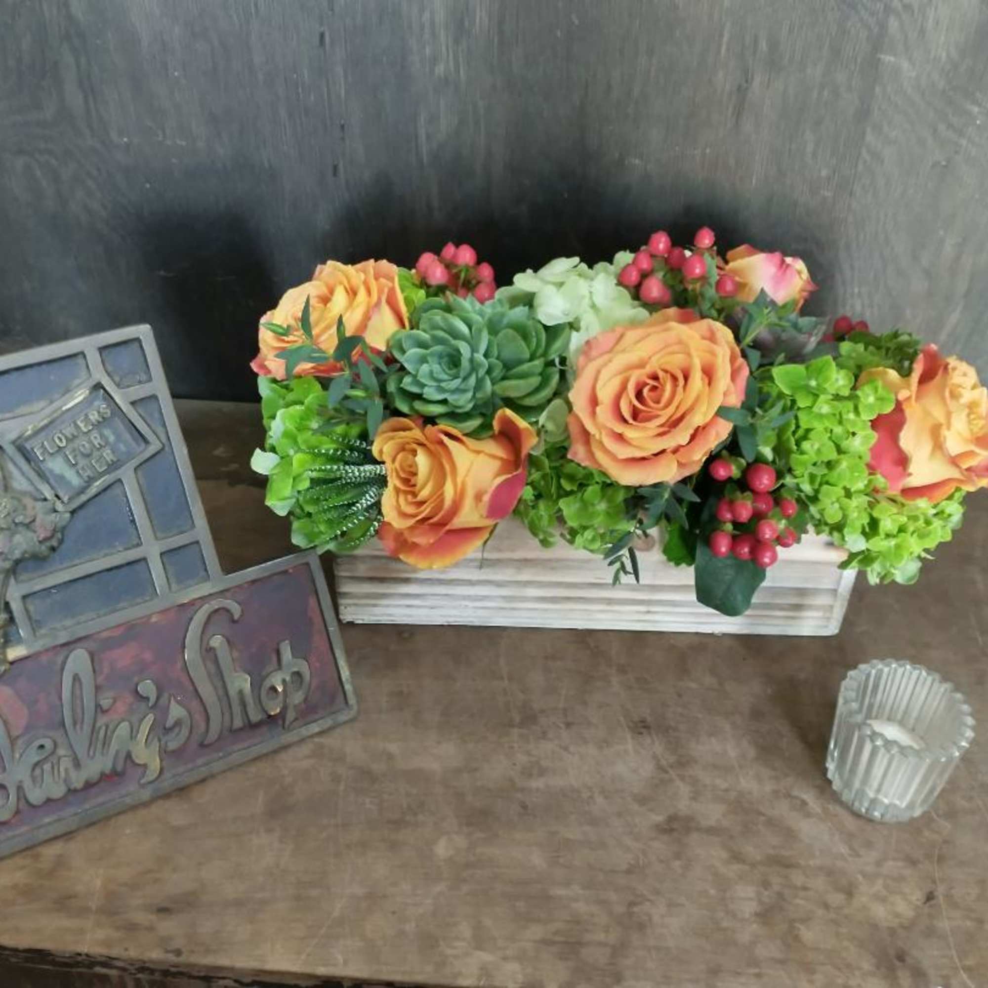 Orange roses and succulents in a white wooden box
