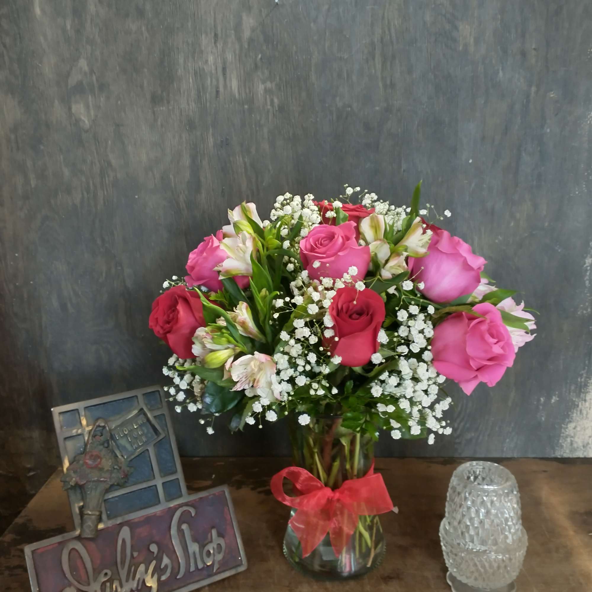 Bouquet of pink and red roses in a glass vase with a red ribbon