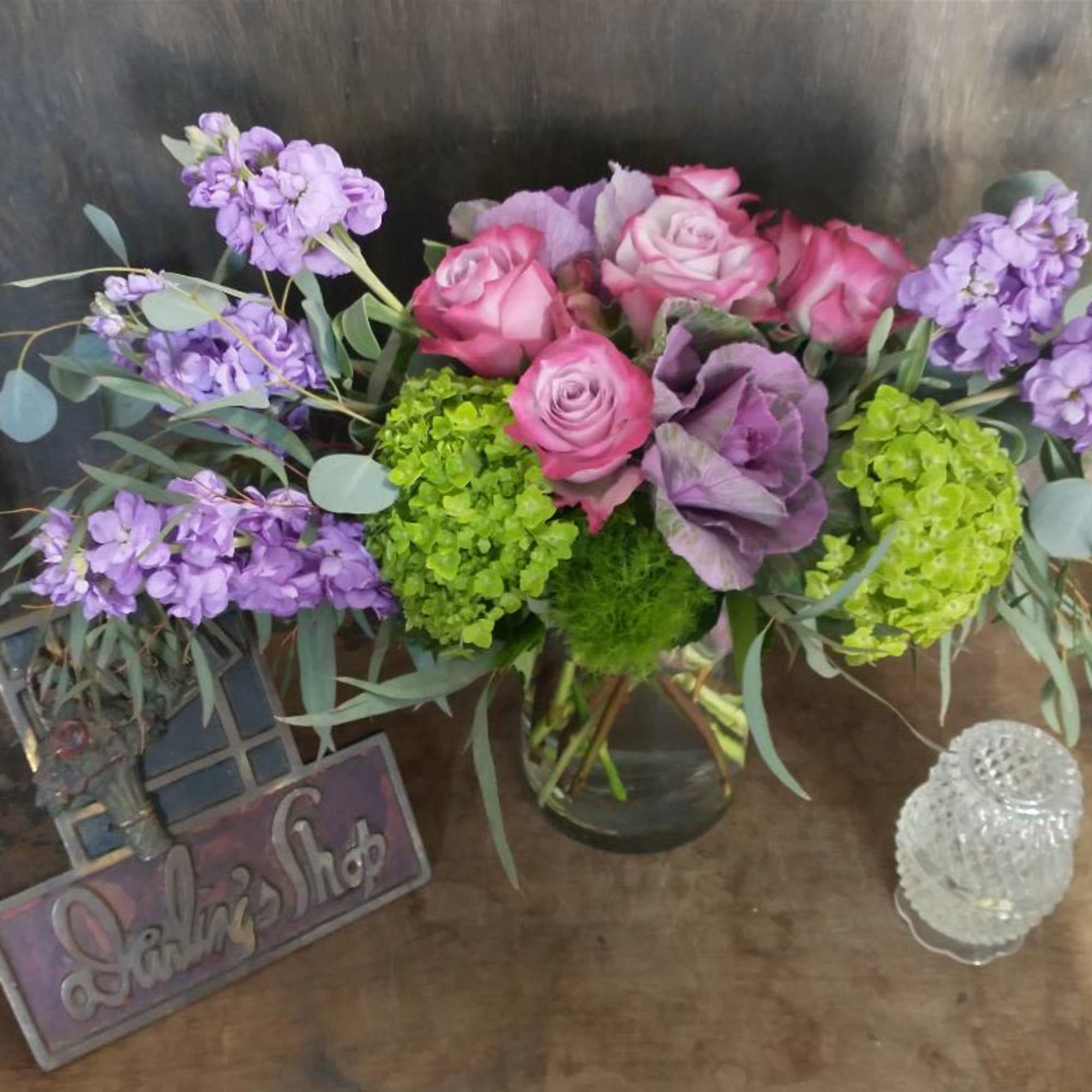 Pink roses and purple flowers arranged in a glass vase